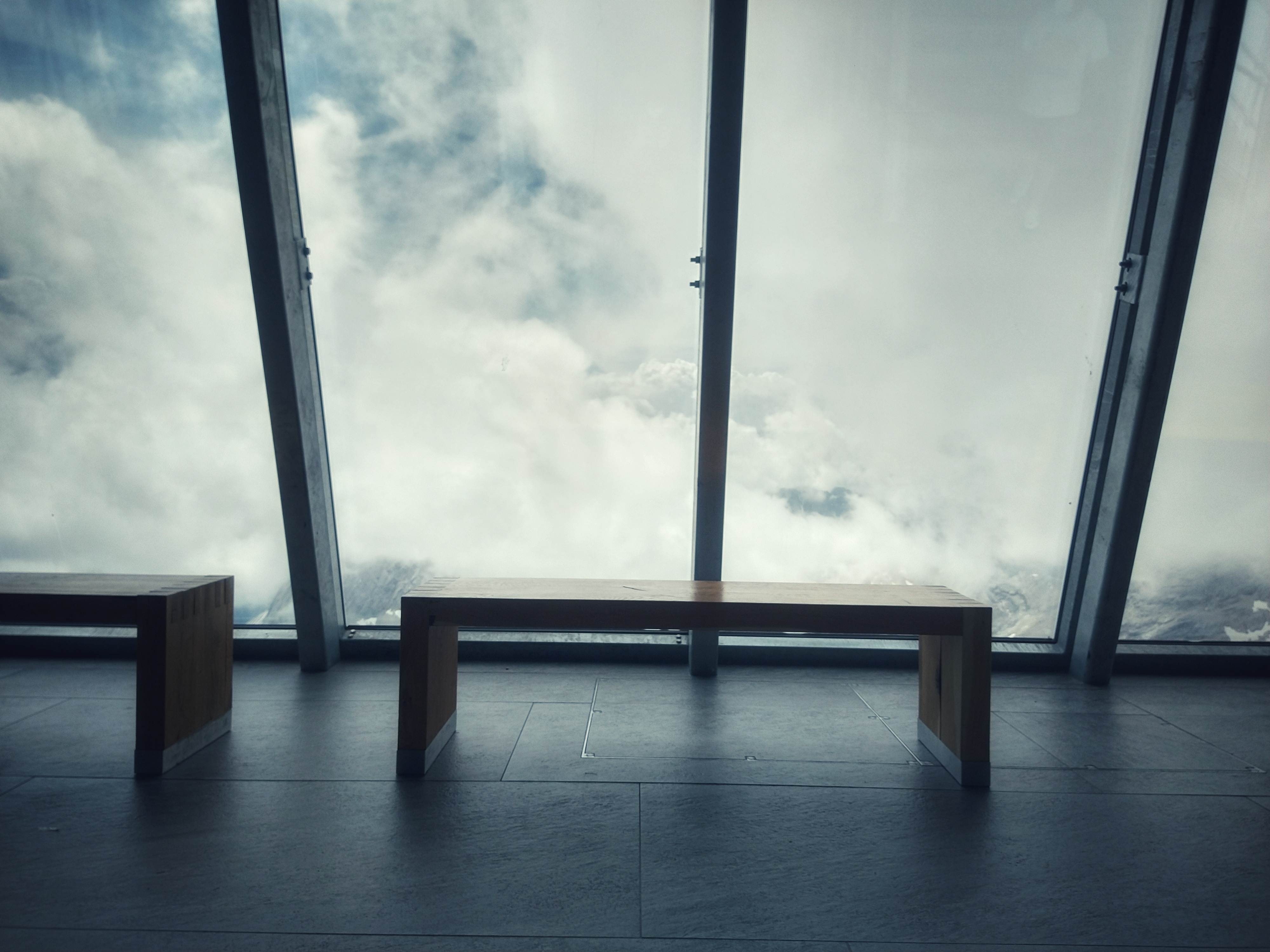 Pench in front of large windows facing the mountain tops. The view is obstructed by clouds