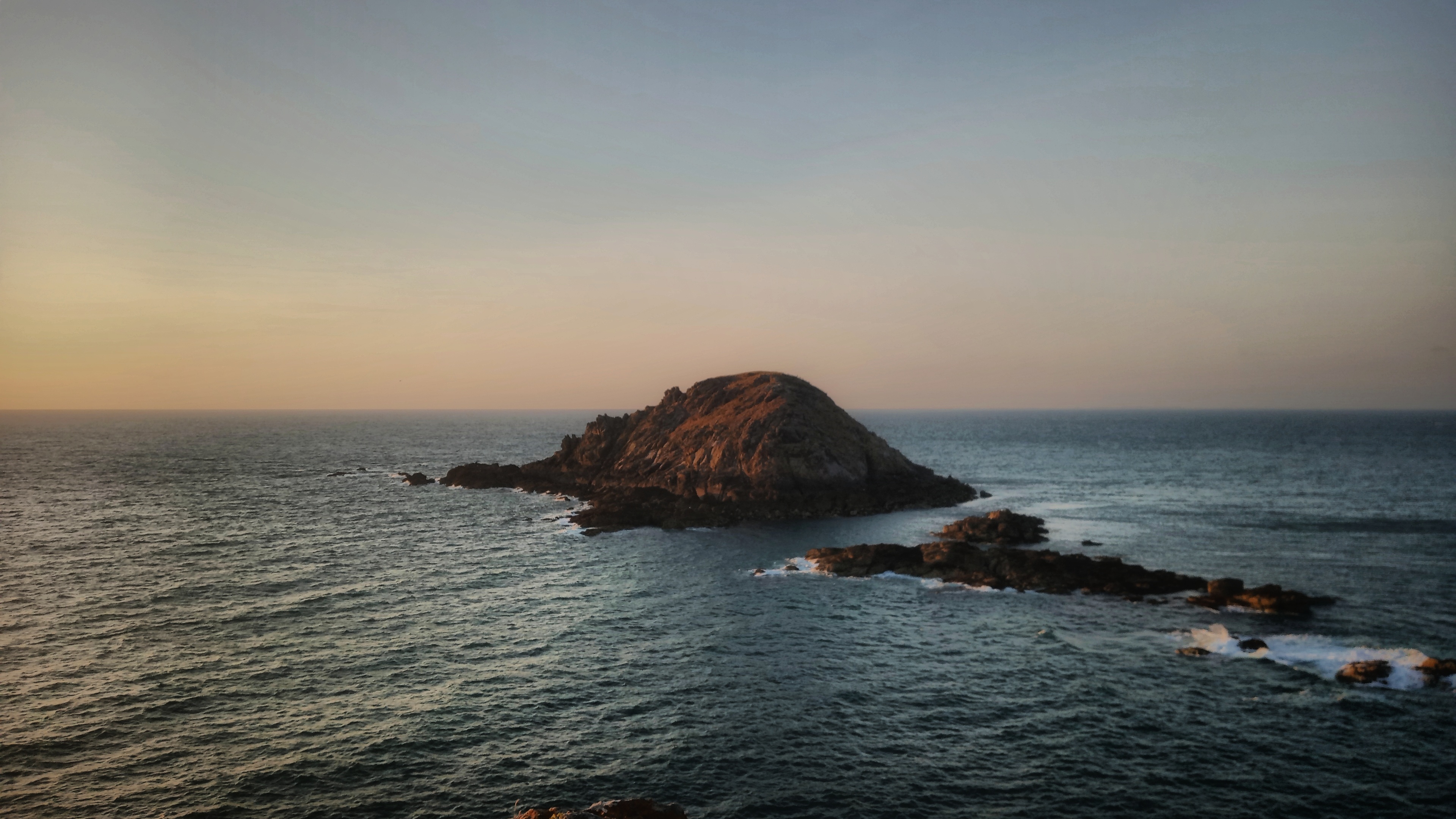 Small island in water. The sunset is colouring the grass a orange-green