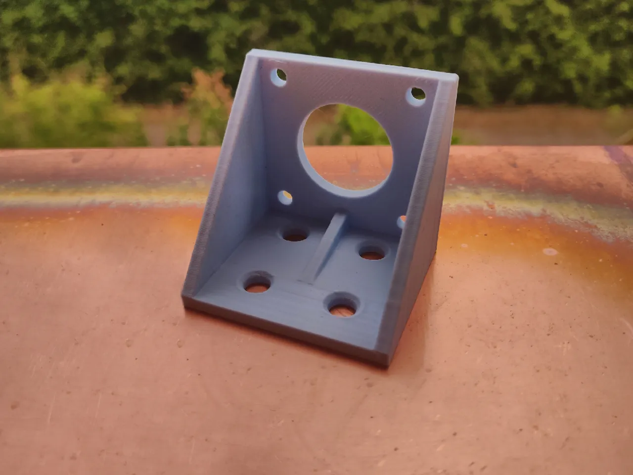 3D-printed stepper mount sitting on a copper plate. The extrusion holes are facing down, whilst the camera points directly at the stepper cutout