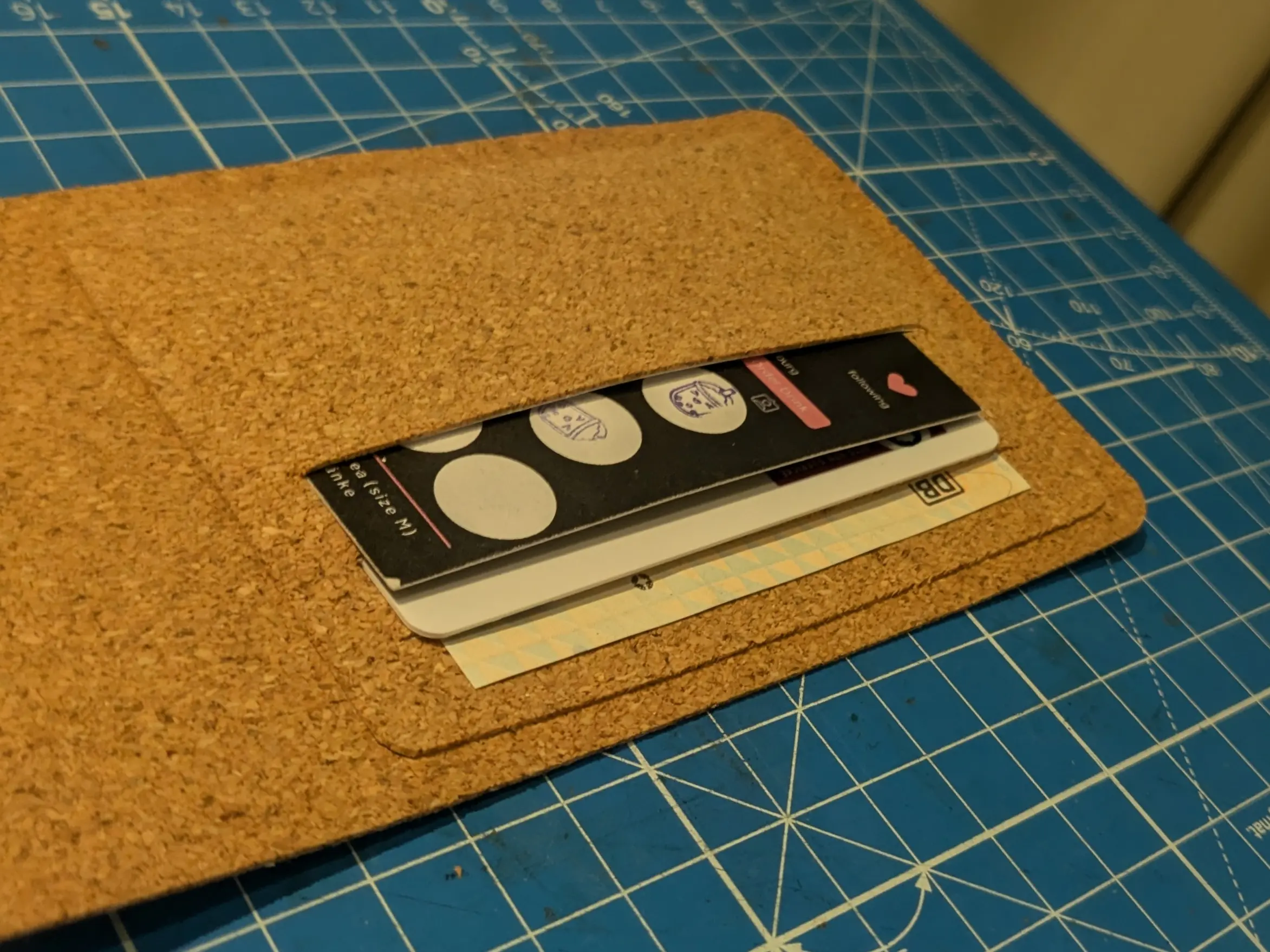 Picture showing the ID card holder glued onto the inner sleeve (second long piece of cork).
Each of the three slots has a card in it. About one third of the lowest one is seen sticking out. and the other two cards each extend roughly 5 mm past the previous card.