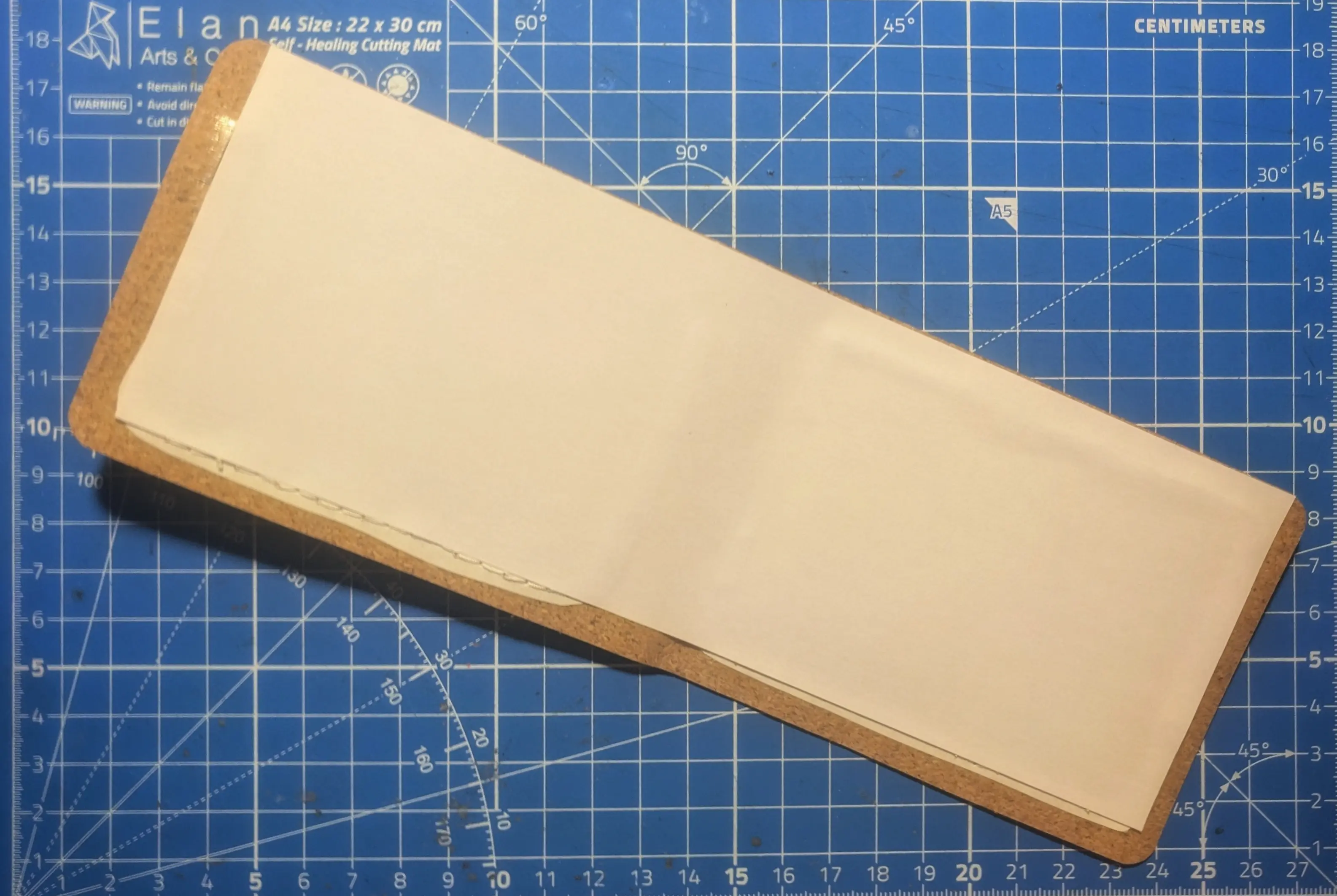 Inside of the stretched inner sleeve.
Similarly to the outer sleeve, a paper lining has been glued on the inside, leaving open space on the left, bottom, and right-hand side.
Through the paper, you can see the shimmer of the old adhesive still being in place where the yarn accents were stitched on.