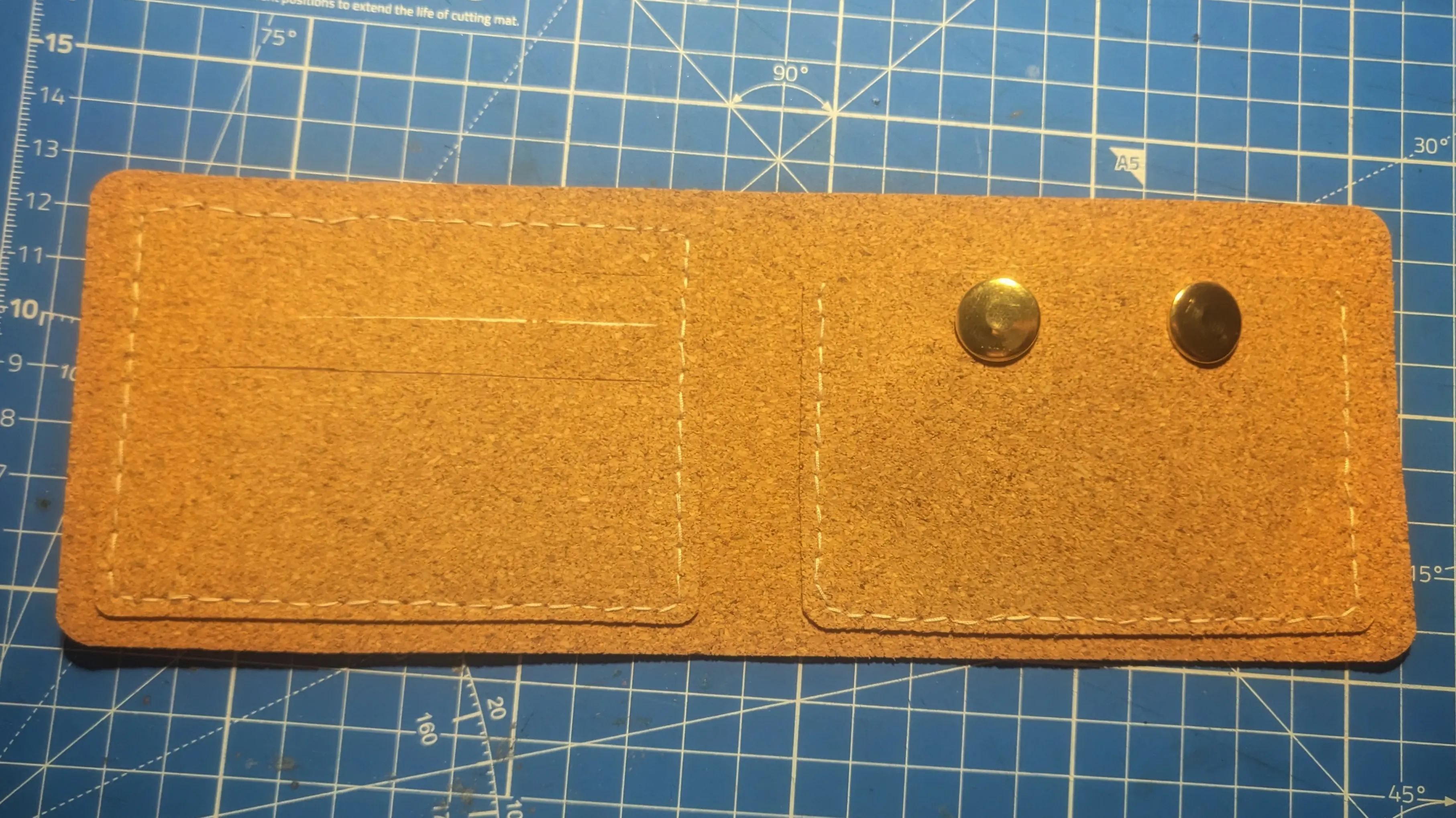 Top-down view of the opened wallet, showing the white yarn outline along the outer edge of the ID card holder and along the left, bottom, and right of the coin pocket.