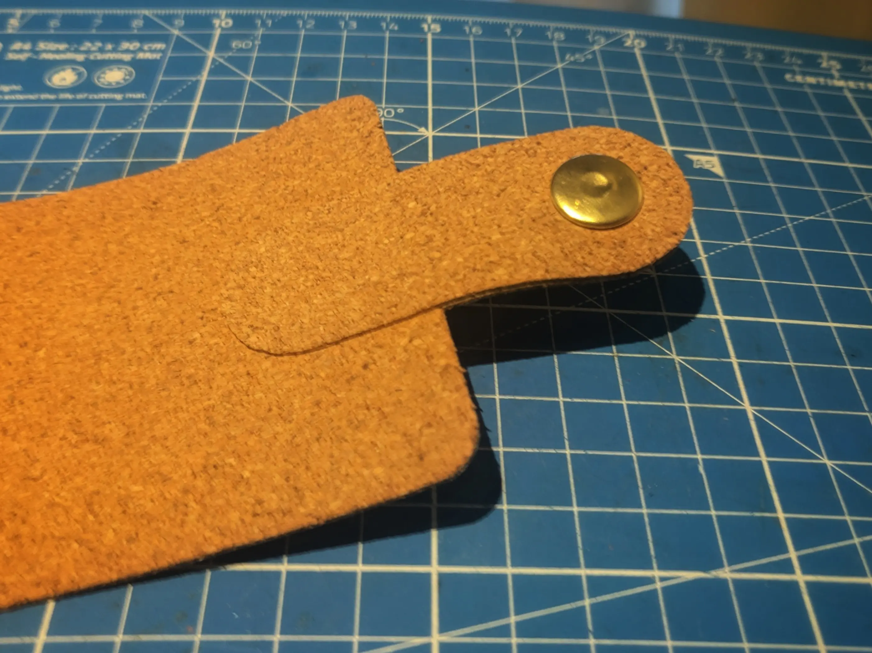 The latch piece glued to the outer sleeve (one of the two large cork rectangles). It is centered along the short side and overlapping it by one third.