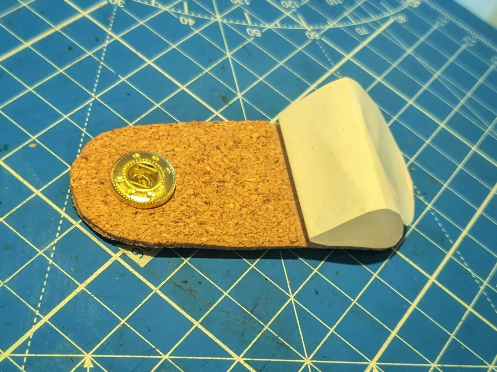 The same latch piece flipped upside down, showing the female end of a snapping button.