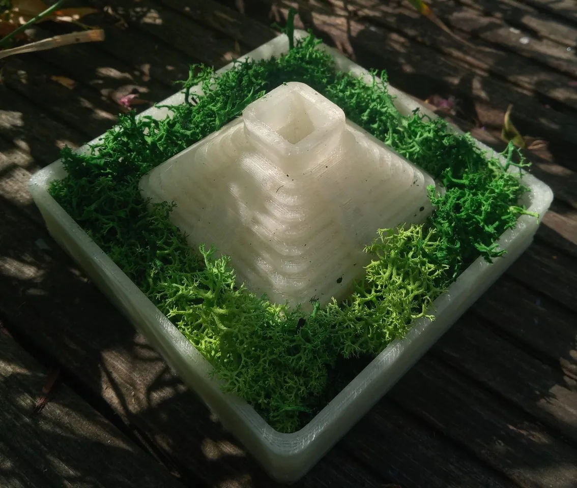 Pyramid planter from a 45 degree angle. The lower patch has been filled with a mossy plant. The sunlight highlights the steps leading up the pyramid