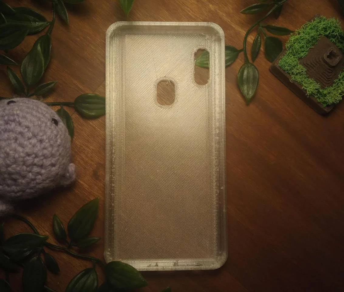 Phone case sitting on wooden desk next to a crochet amigurumi and a small planter