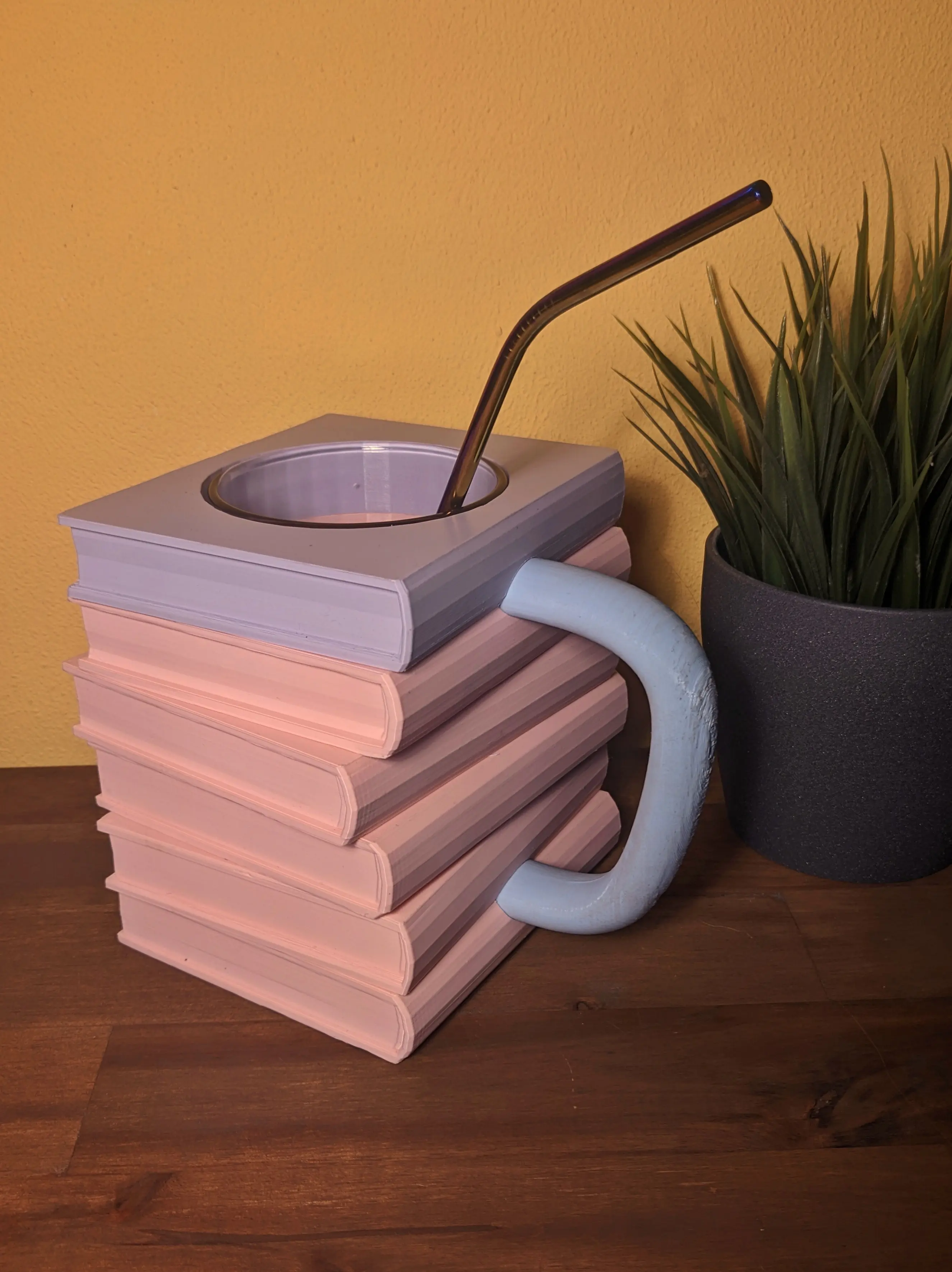 Fully assembled mug with a glass inside. A drinking straw has been placed inside the glass.
The books have been stacked in the correct order with the handle glued on from the side.
The mug is facing the camera from an angle, showing both the handle and one side of the books.