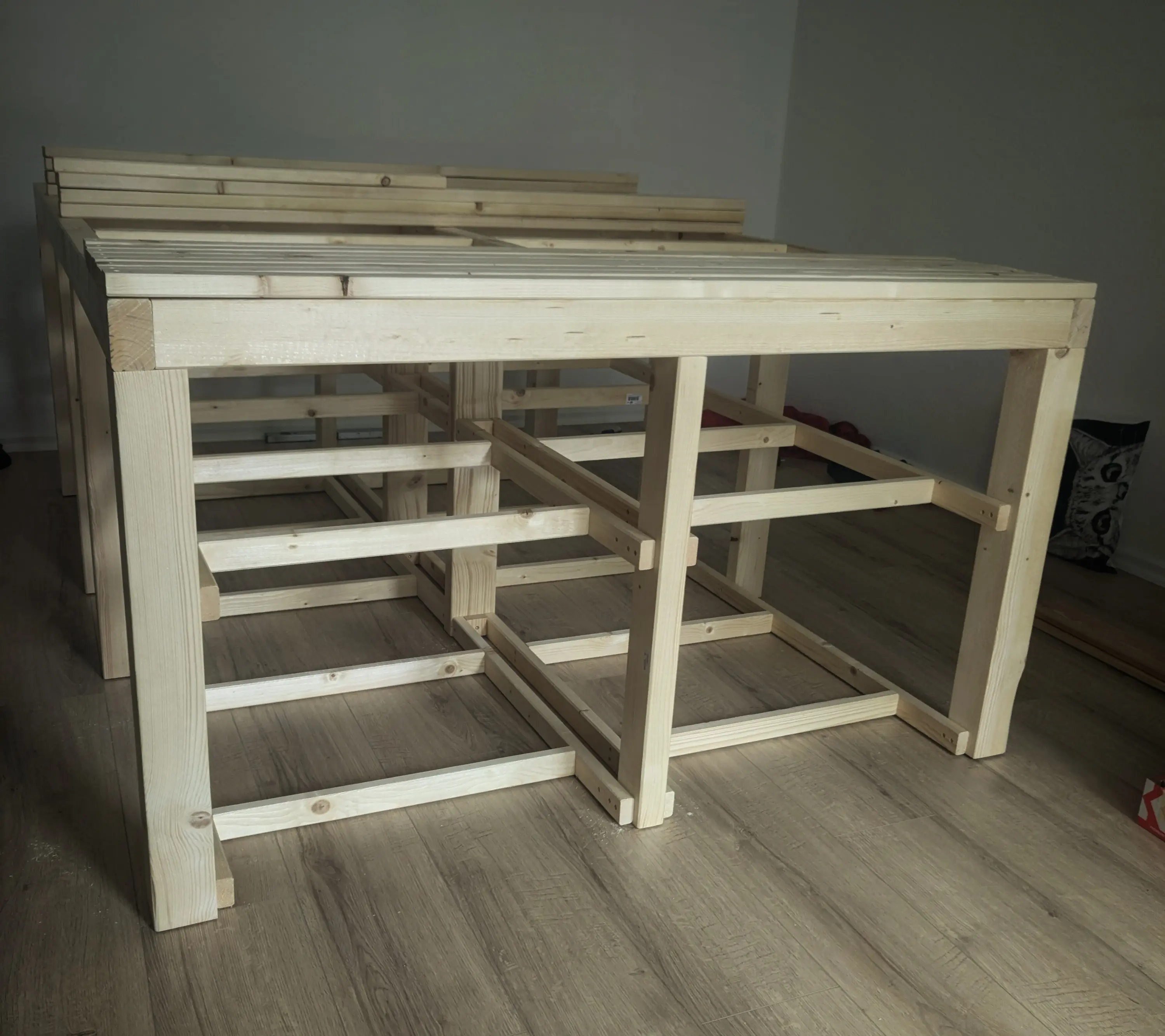 The same wooden structure, but the horizontal beams have support legs.
Additionally, smaller beams have been screwed in place on two layers, acting as a support for a future shelf inlay.
On the top of the horizontal beams, smaller wooden beams span all across the bed. A stack of more such beams can be made further towards the back of the bed The same wooden structure, but the horizontal beams have support legs.
Additionally, smaller beams have been screwed in place on two layers, acting as a support for a future shelf inlay.
On the top of the horizontal beams, smaller wooden beams span all across the bed. A stack of more such beams can be made further towards the back of the bed