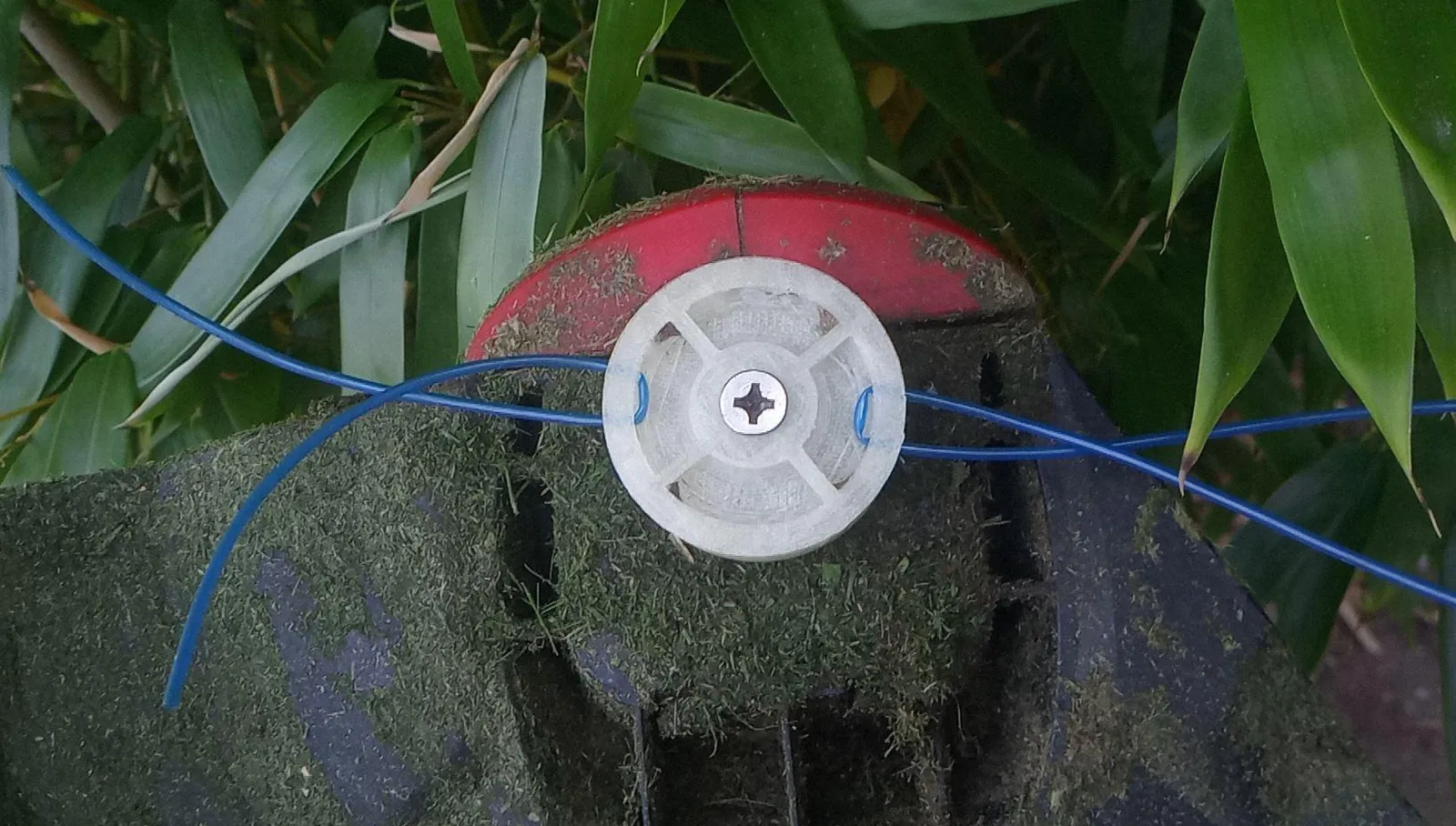 3d printed cylinder shape attached to trimmer head, with four elastic strings sticking out on two sides