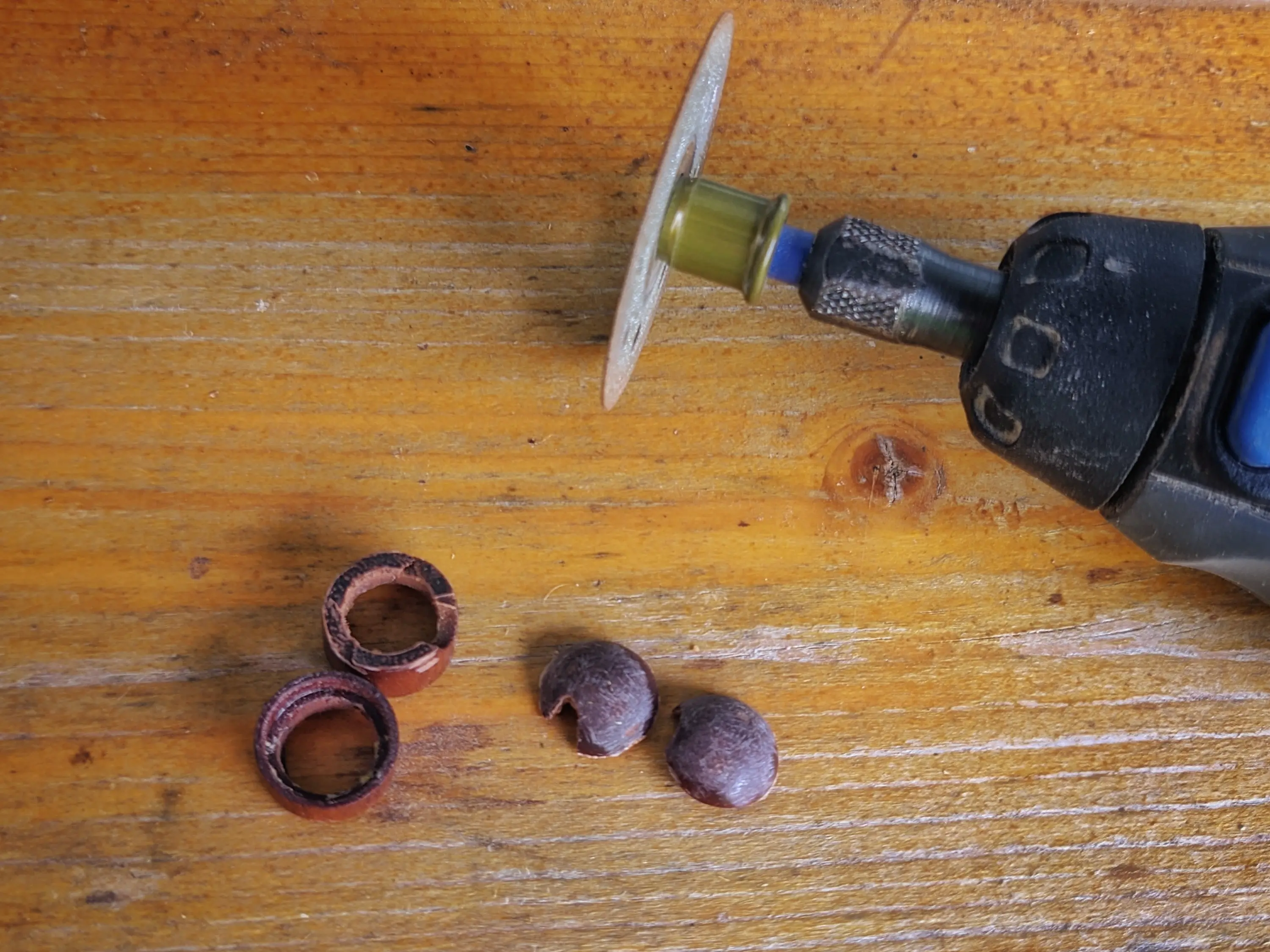 Multiple wood pieces lying next to a Dremel tool with a rotary wheel attachted.
The wooden pieces are placed in pairs of two: two lower cylindrical pieces and two dome-shaped pieces from the top.