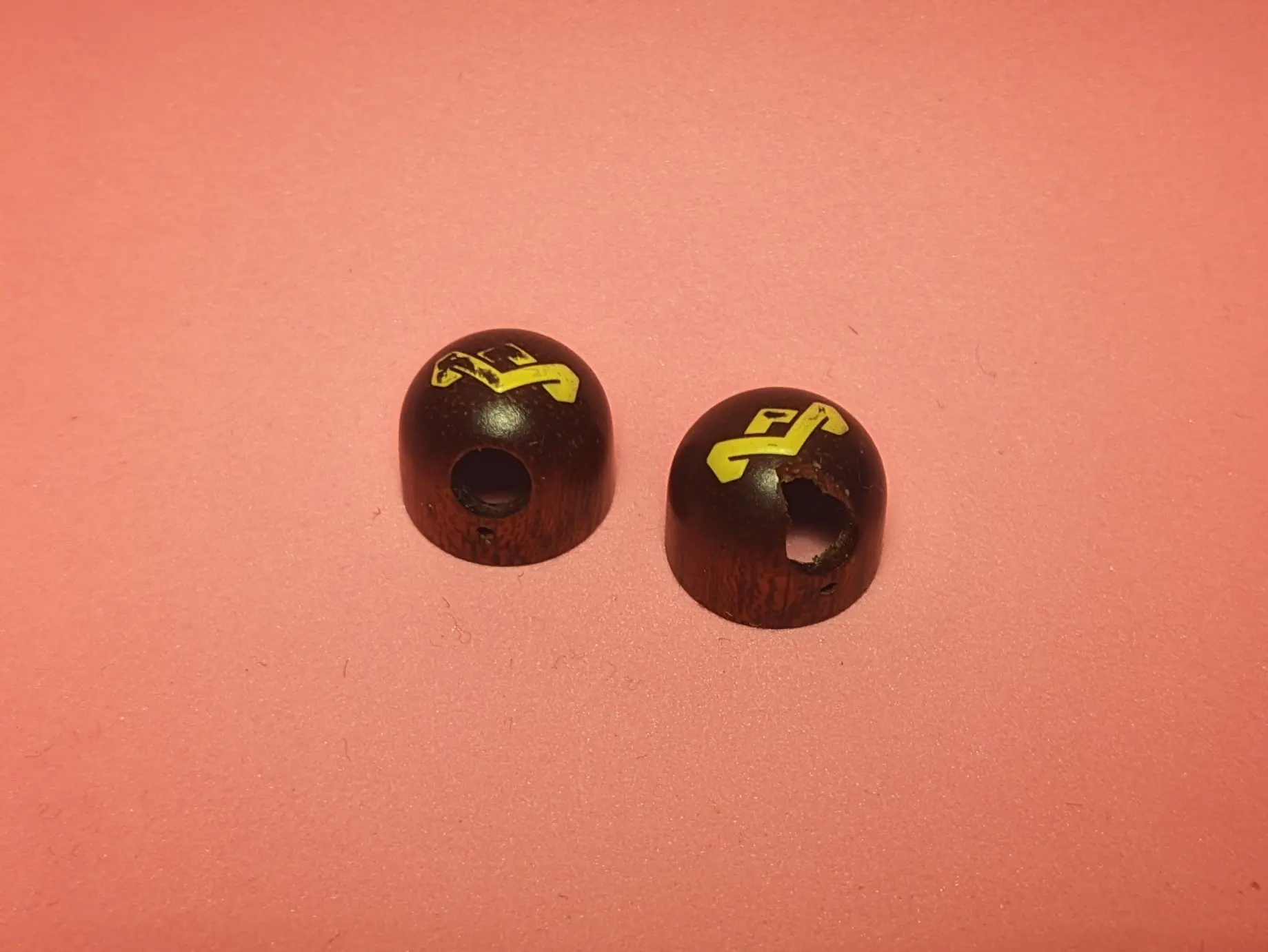 Wooden shell pieces extracted from the headphone earpieces.
They have been placed with the flat side facing down. The rounded dome section is facing up.
The wire cutout holes on the side of the shells are facing the camera.