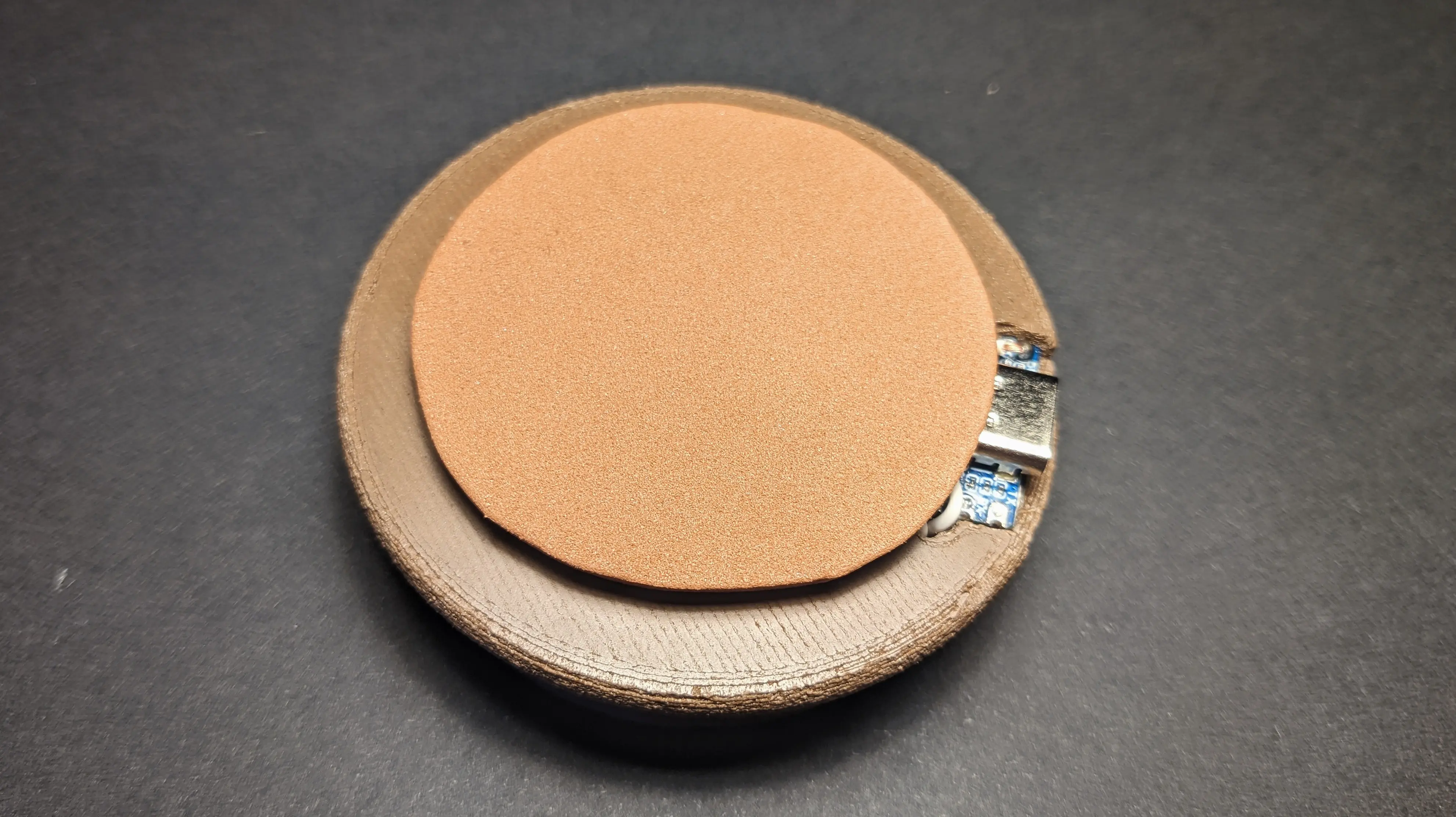A circular brown foam cutout glued to the foam adhesive strips.
Only the outer section of the base is visible with parts of the USB-C port.