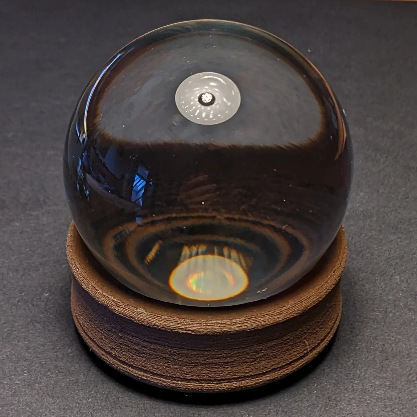 Picture of switched-off GlowOrb, with a crystal ball placed on the base.
A lamp above reflects in the glass. The ball itself appears dark.