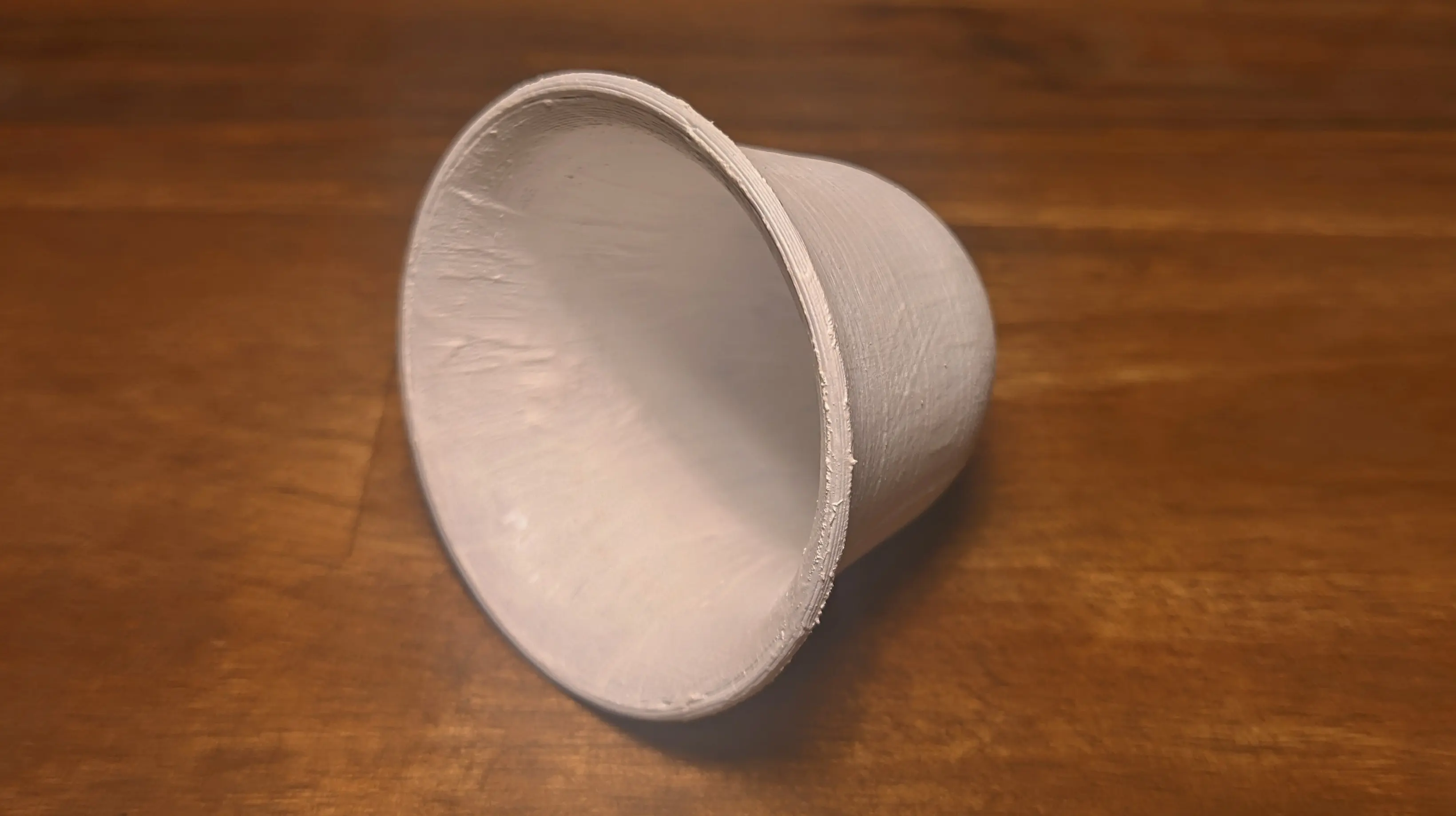 The bell lying on its side with both the inside and outside visible to the camera. Both of them are coloured in white, with some slight bumps where too much color was added.