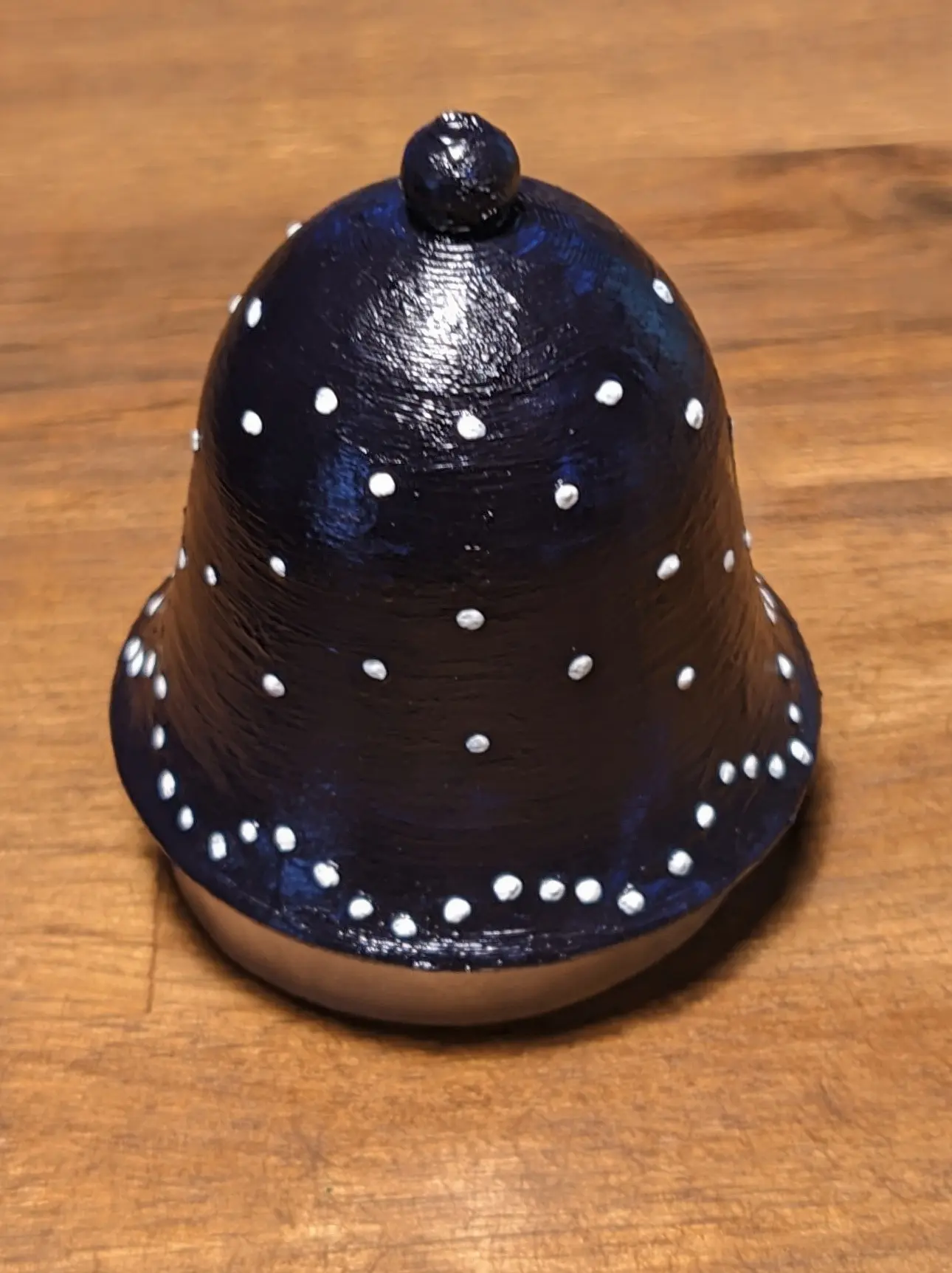 The bell has been placed on the roll of tape again, but this time the surface bumps have painted white dots on them.