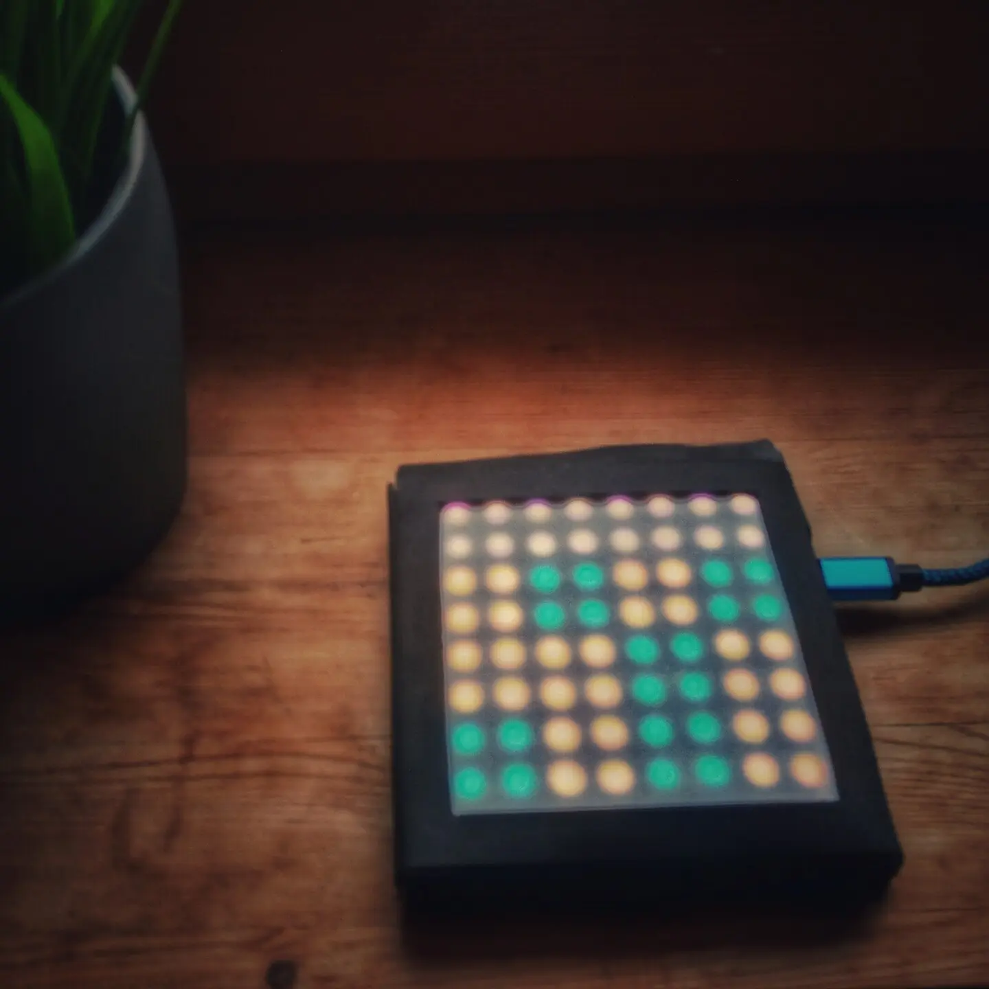 A small flat block placed on a windowsill. The outside of the box is lined in black foam. Groups of four LEDs can be seen shining through the top white foam layer. A cable is plugged into the box and running off to the side.