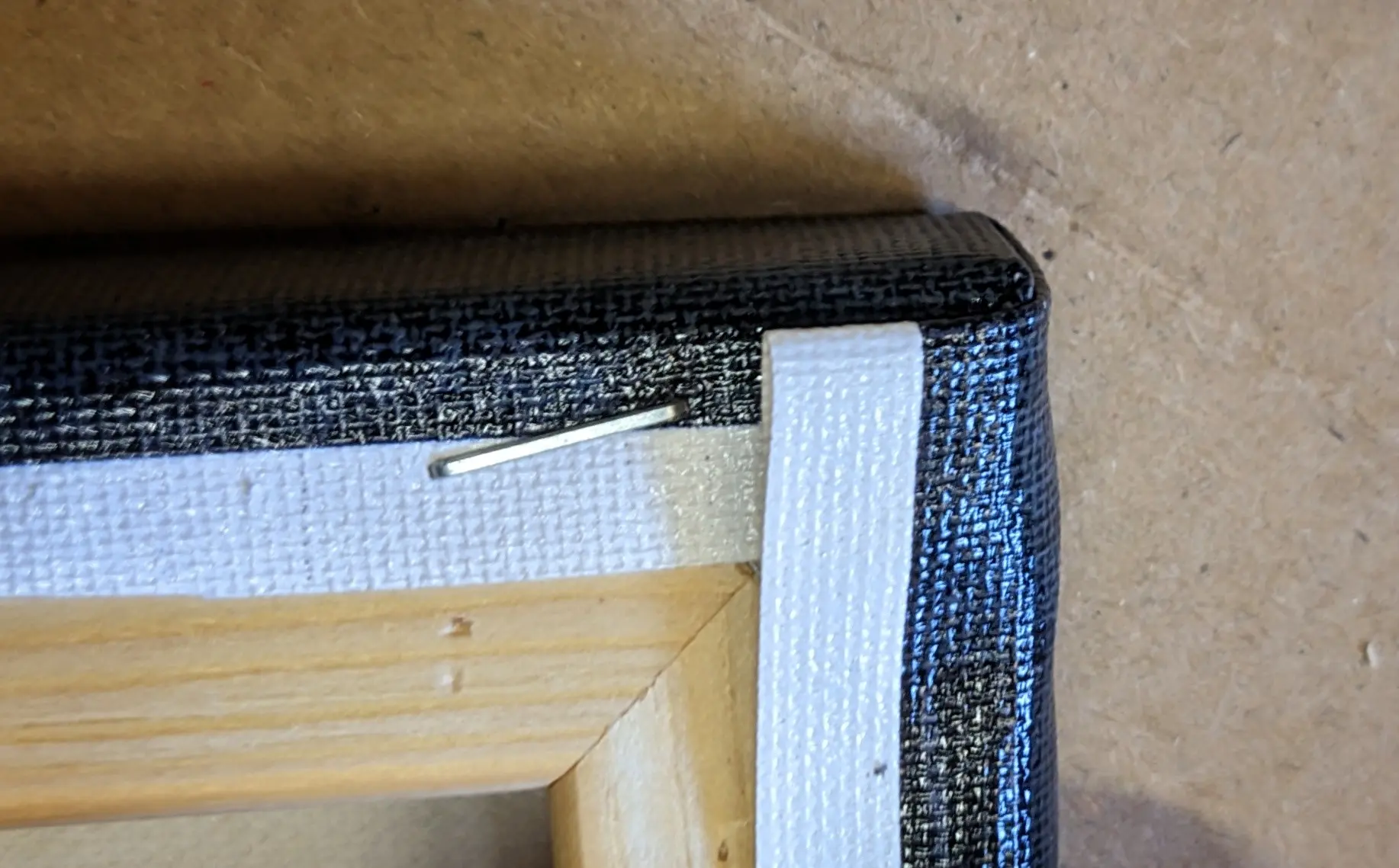 The folded region from the previous image has been pressed flat against the frame, and the excess material has been folded over the back.