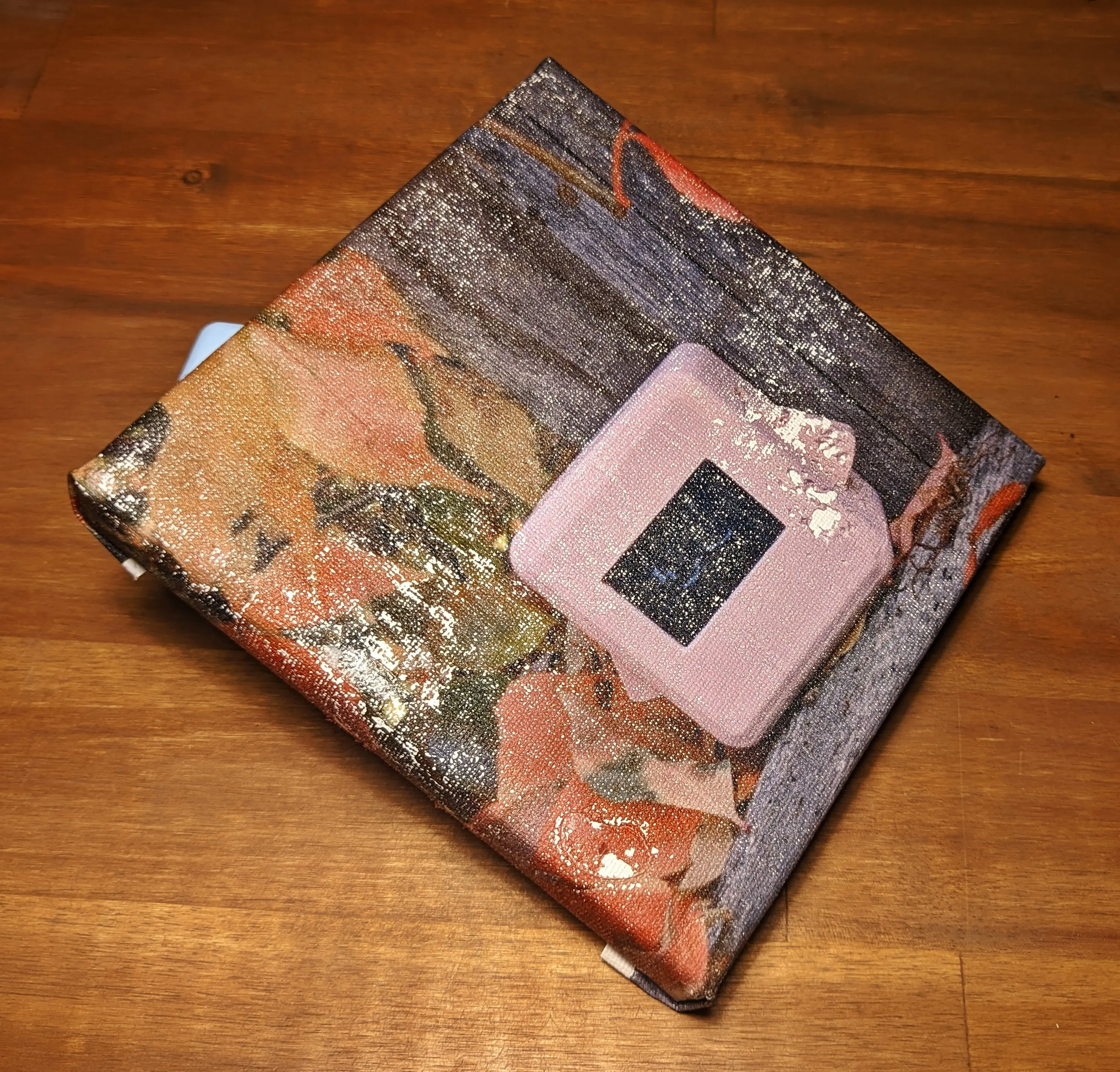 Finished canvas propped up on a blue block, showing the canvas from a slight angle.
The printed image still has the same vivid and deep colors as earlier,
and seems to have kept its sharpness and high resolution.
You can also make out the canvas pattern underneath.
Sadly, a lot of the image is missing and appears to have been ripped out, revealing the white canvas underneath.