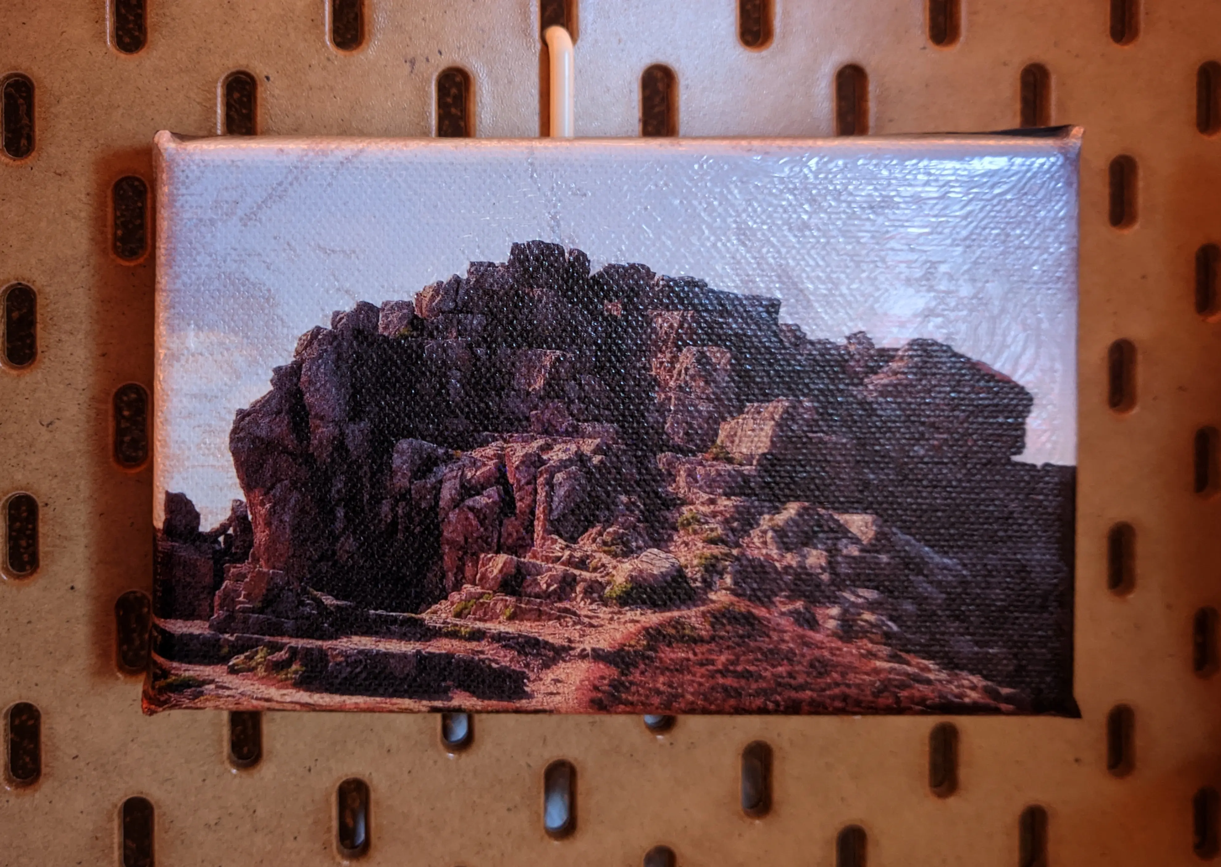 Finished canvas hanging on wall mount. Some air bubbples and crinkles are visible on the top right. You can clearly make out the canvas texture in the darker areas.