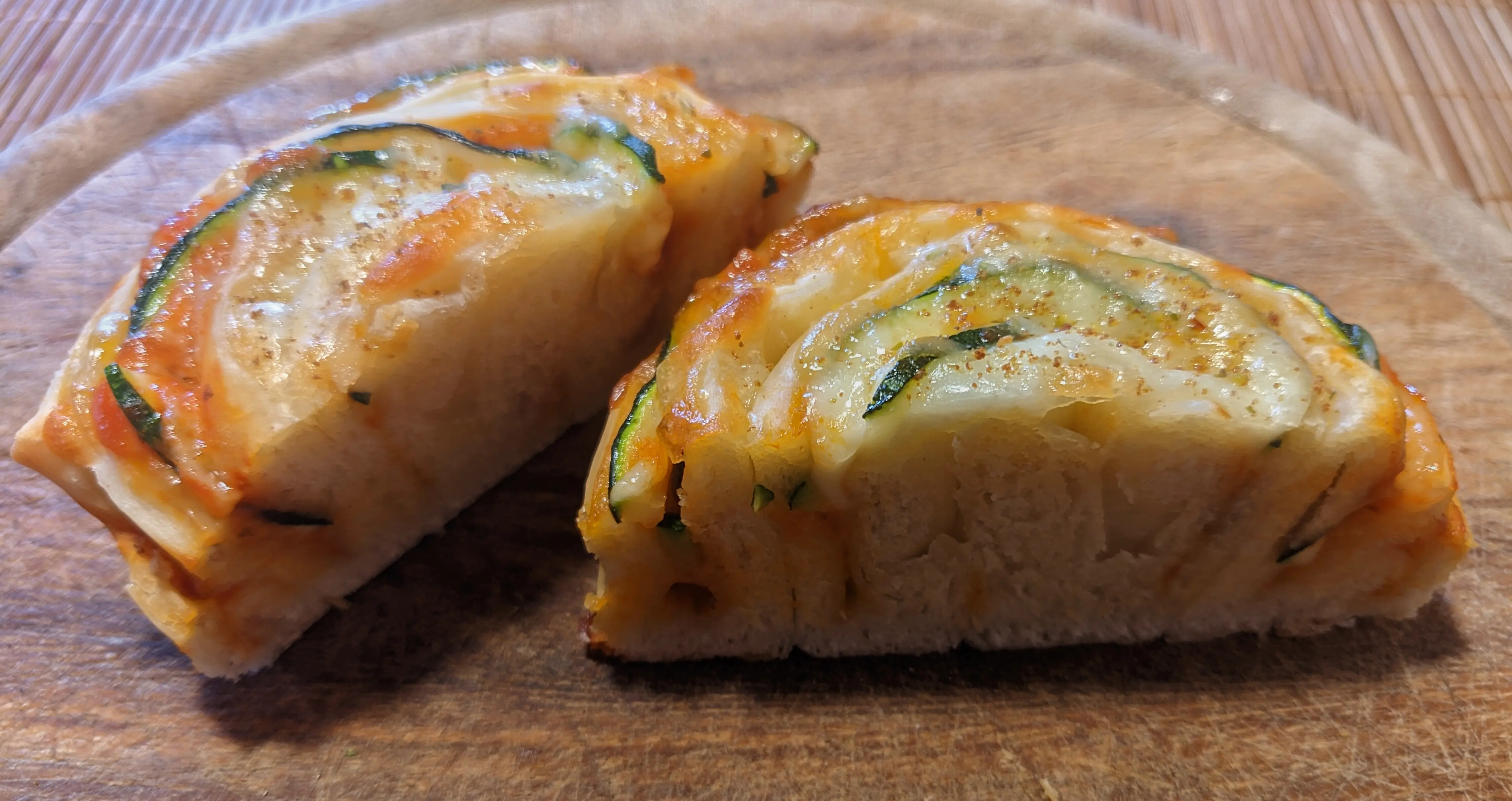A finished roll cut in half, showing the alternating dough and tomato sauce layers.
