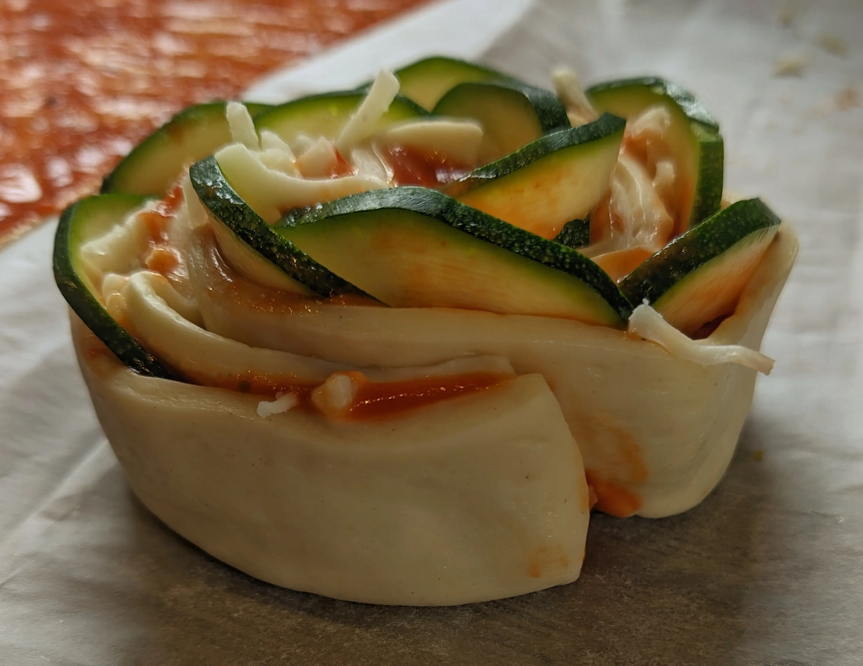Side-view of the finished pizza roll, with zucchinis sticking out, making them look like rose petals.