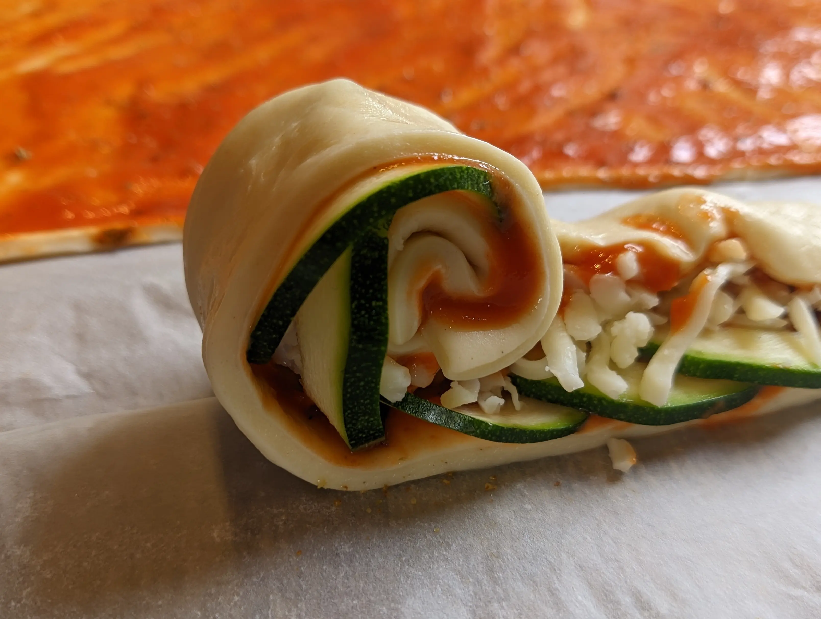 Side-view of the beginning of the pizza roll, showing the doll being rolled in a snail shell pattern.