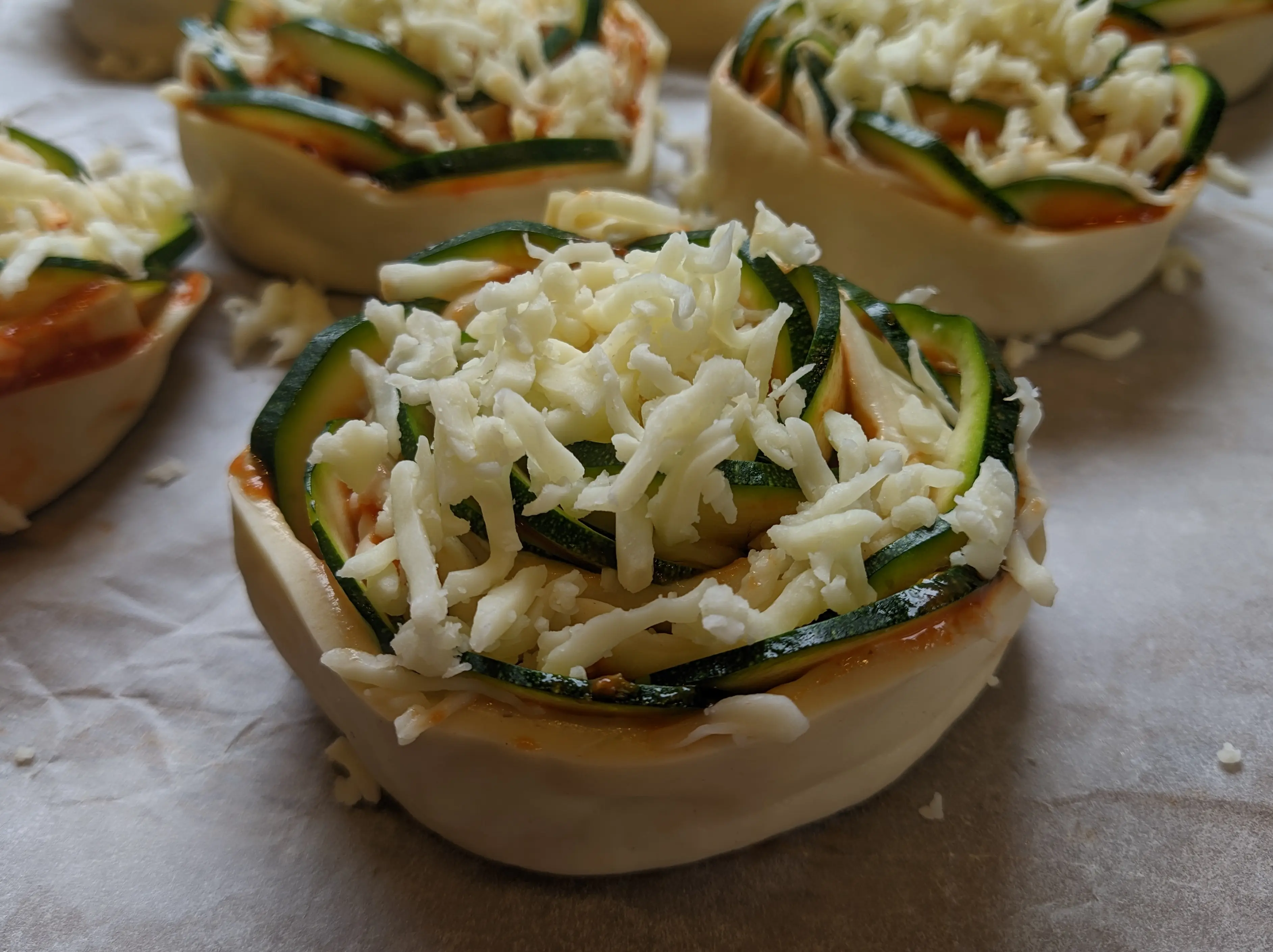 Side-view of the finished roll, showing the rose-petal-like zucchini slices and the grated cheese in closer detail.