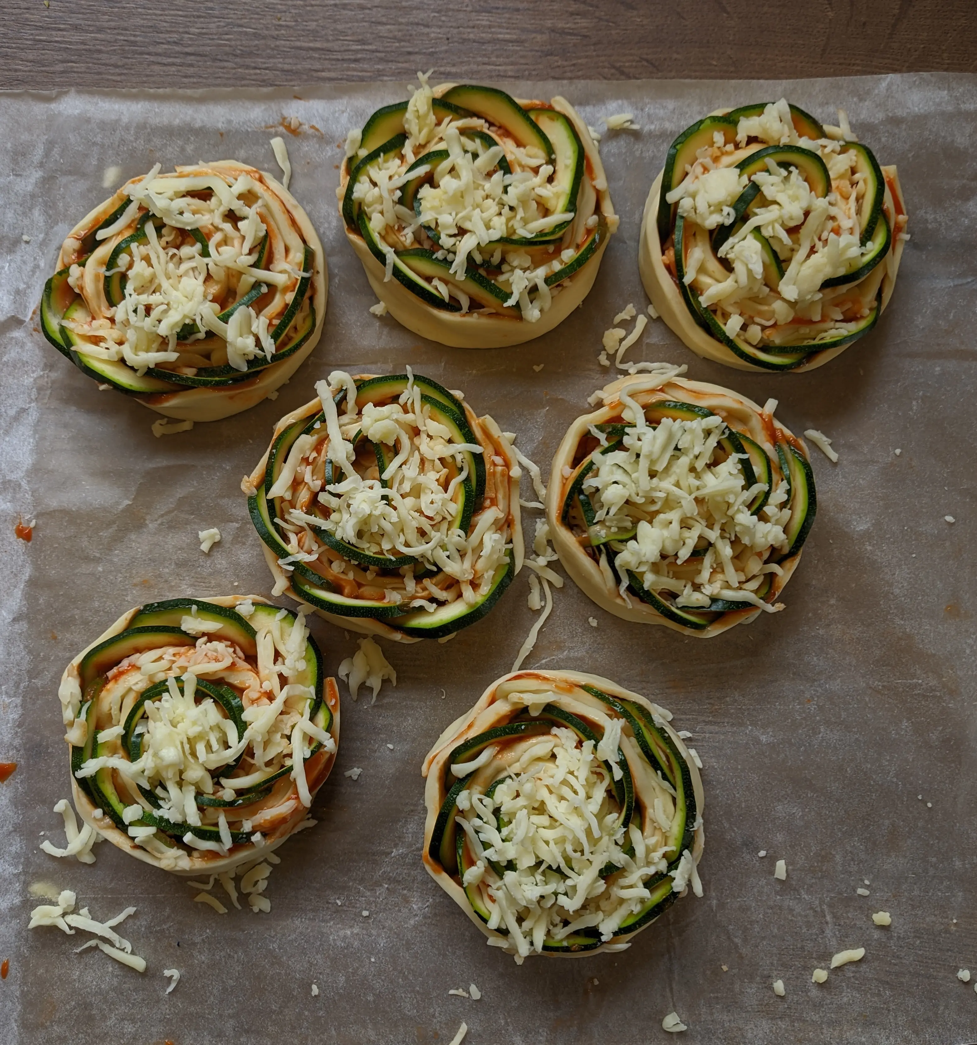 Top-down view of 7 rolls placed on a tray with cheese grated on top.
