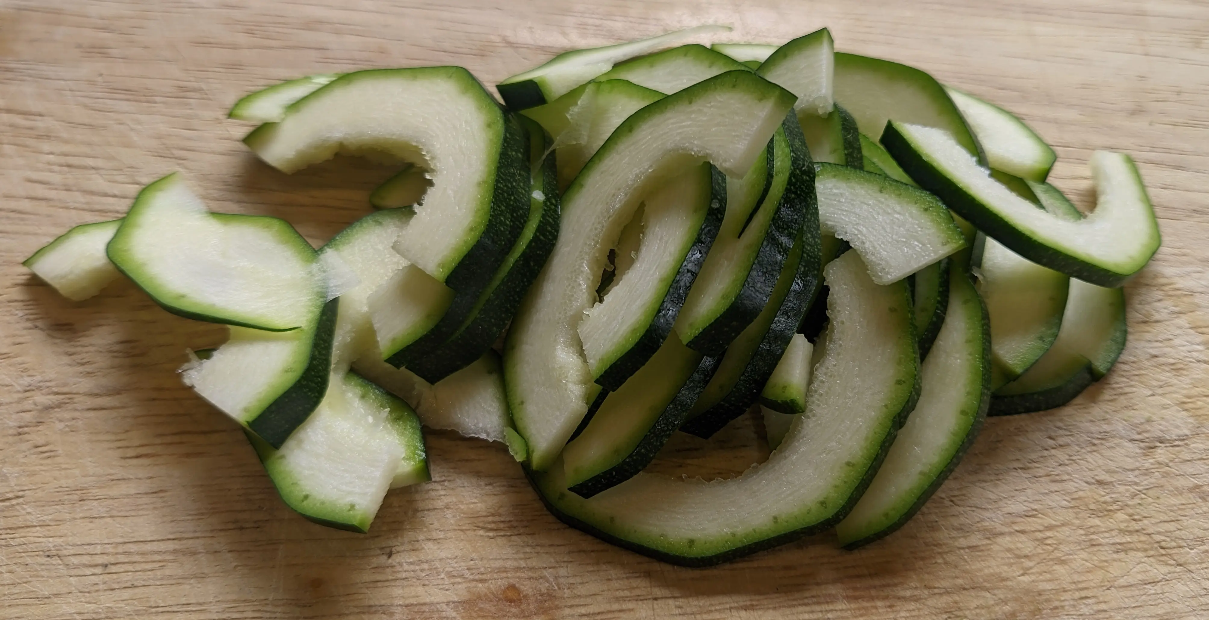 A heap of rainbow-shaped zucchini slices, 1-3 mm wide each