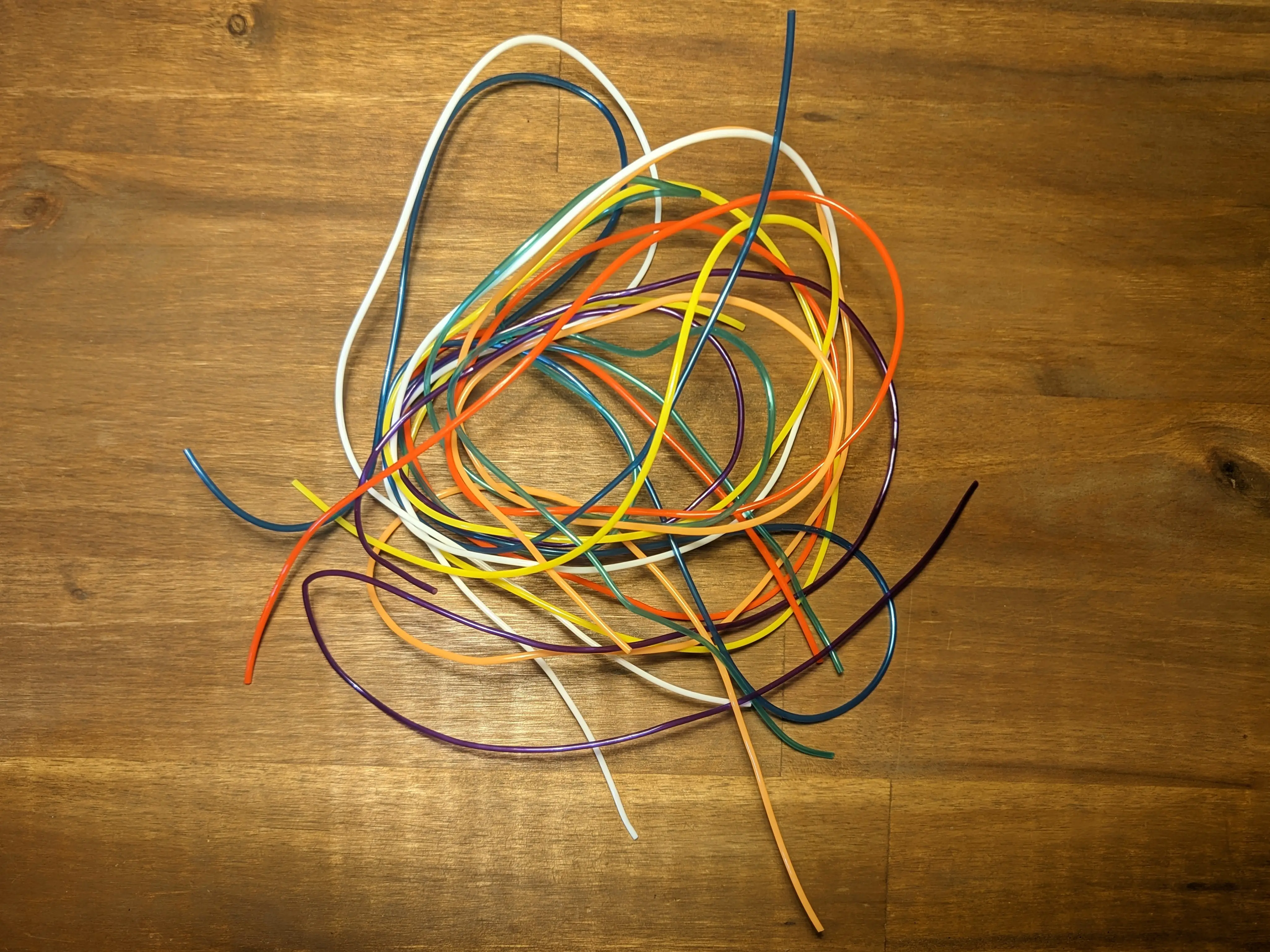 Multiple coloured scoubidou strands chaotically placed on a wooden desk