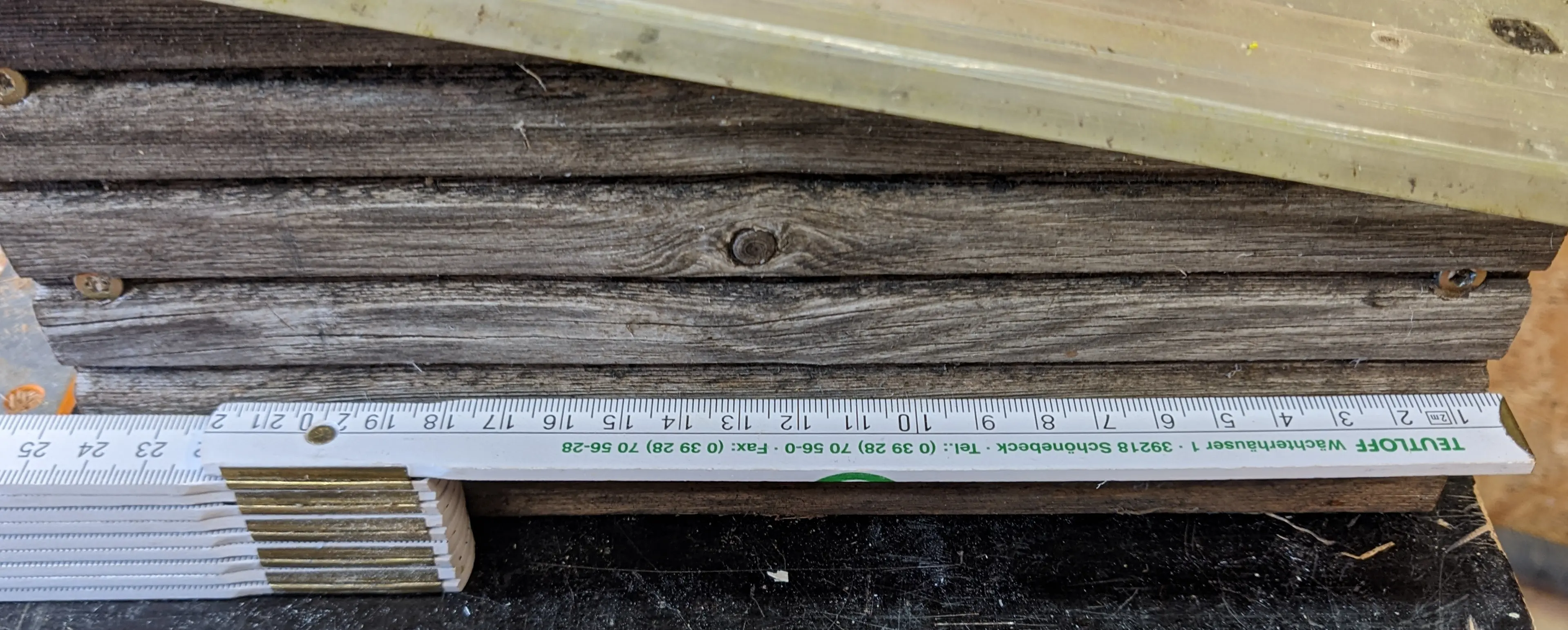 Inch ruler next to the side wall of the wooden hut. It measures 24.5 cm.