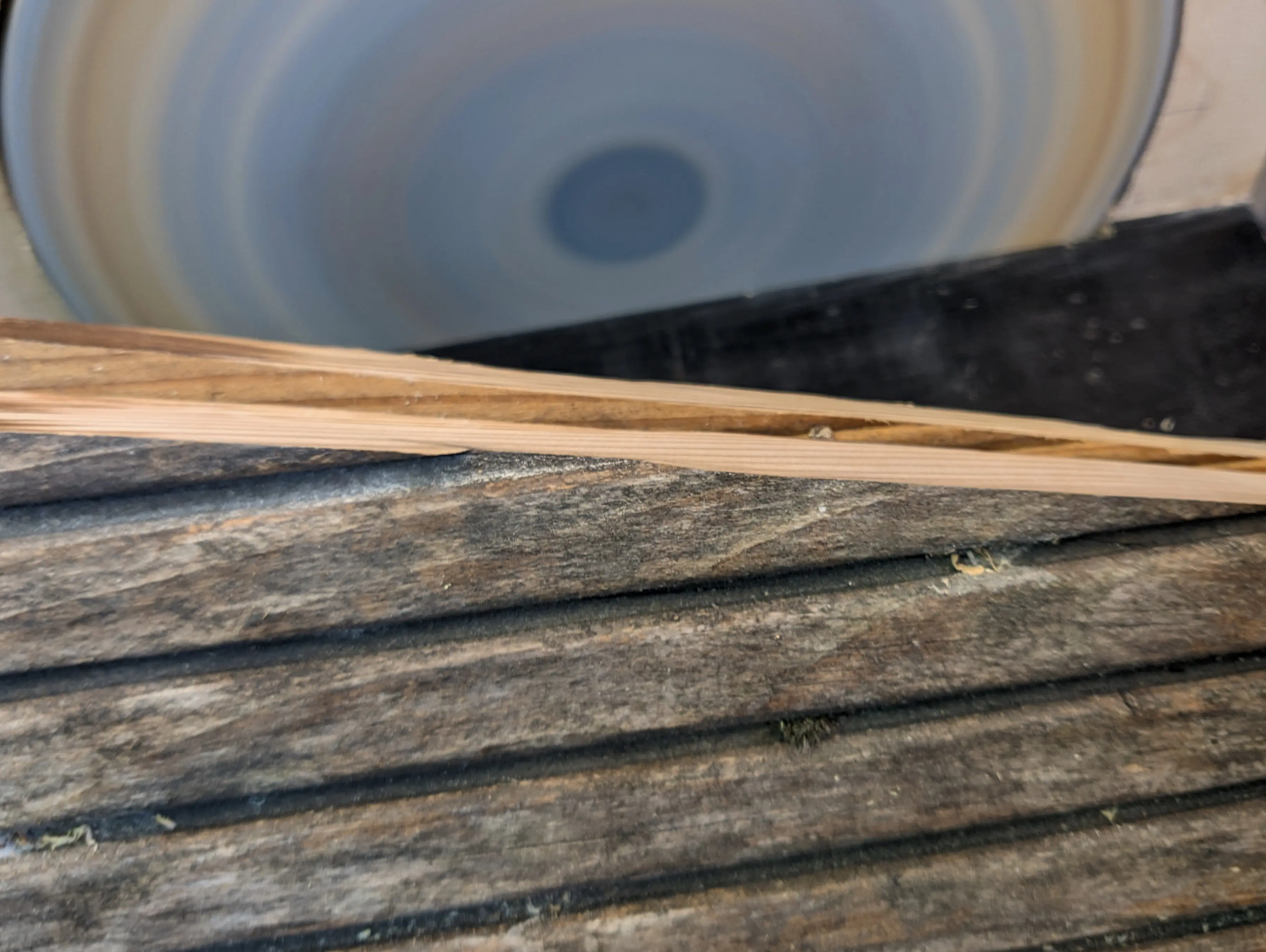 Both wooden side pieces stacked on top of one another, revealing about a 5 mm difference in height. In the background, the sander is already spinning up.