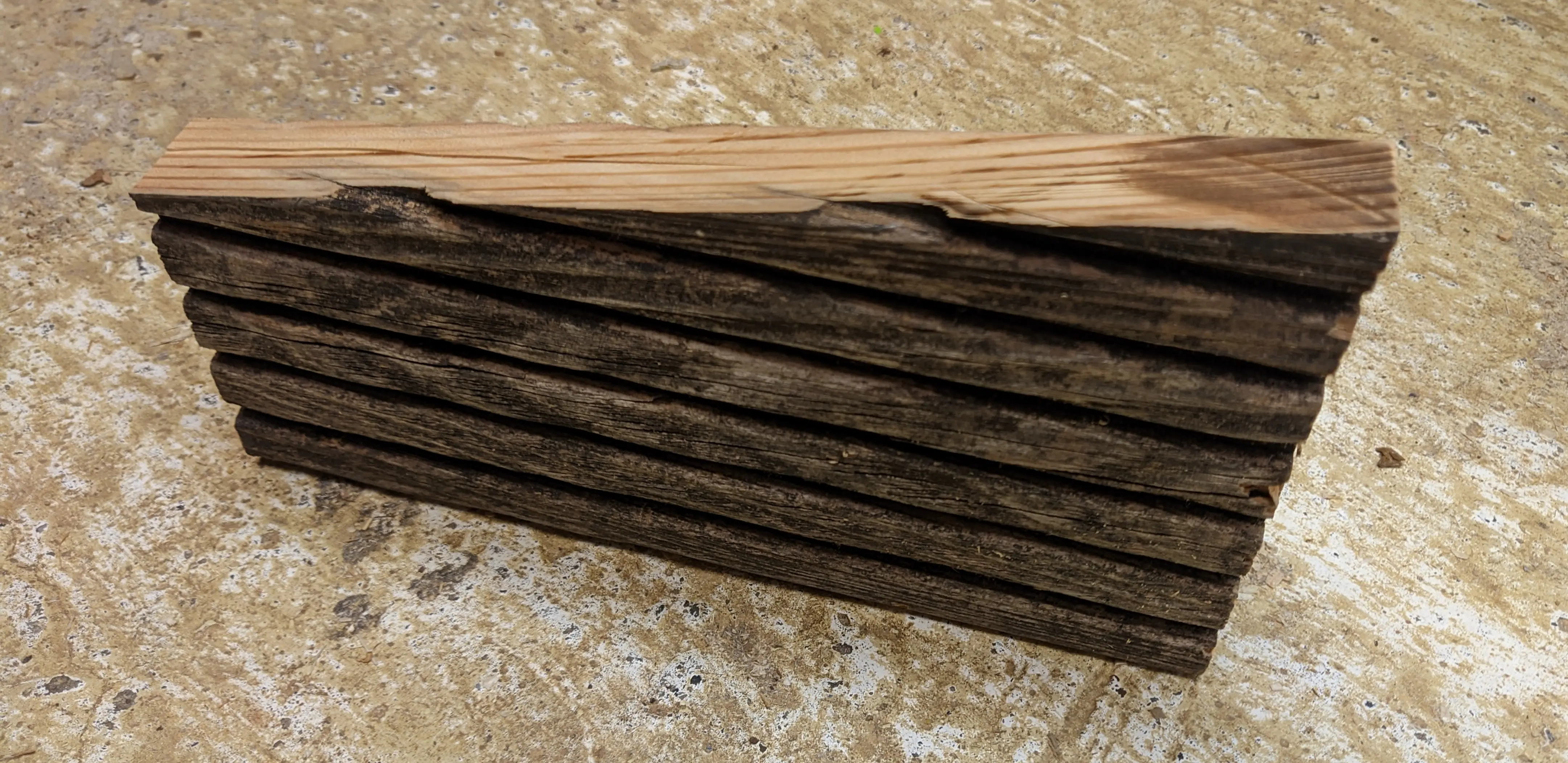 Wooden piece standing on the ground. The piece is taller on the right than on the left, because it was cut at an angle.