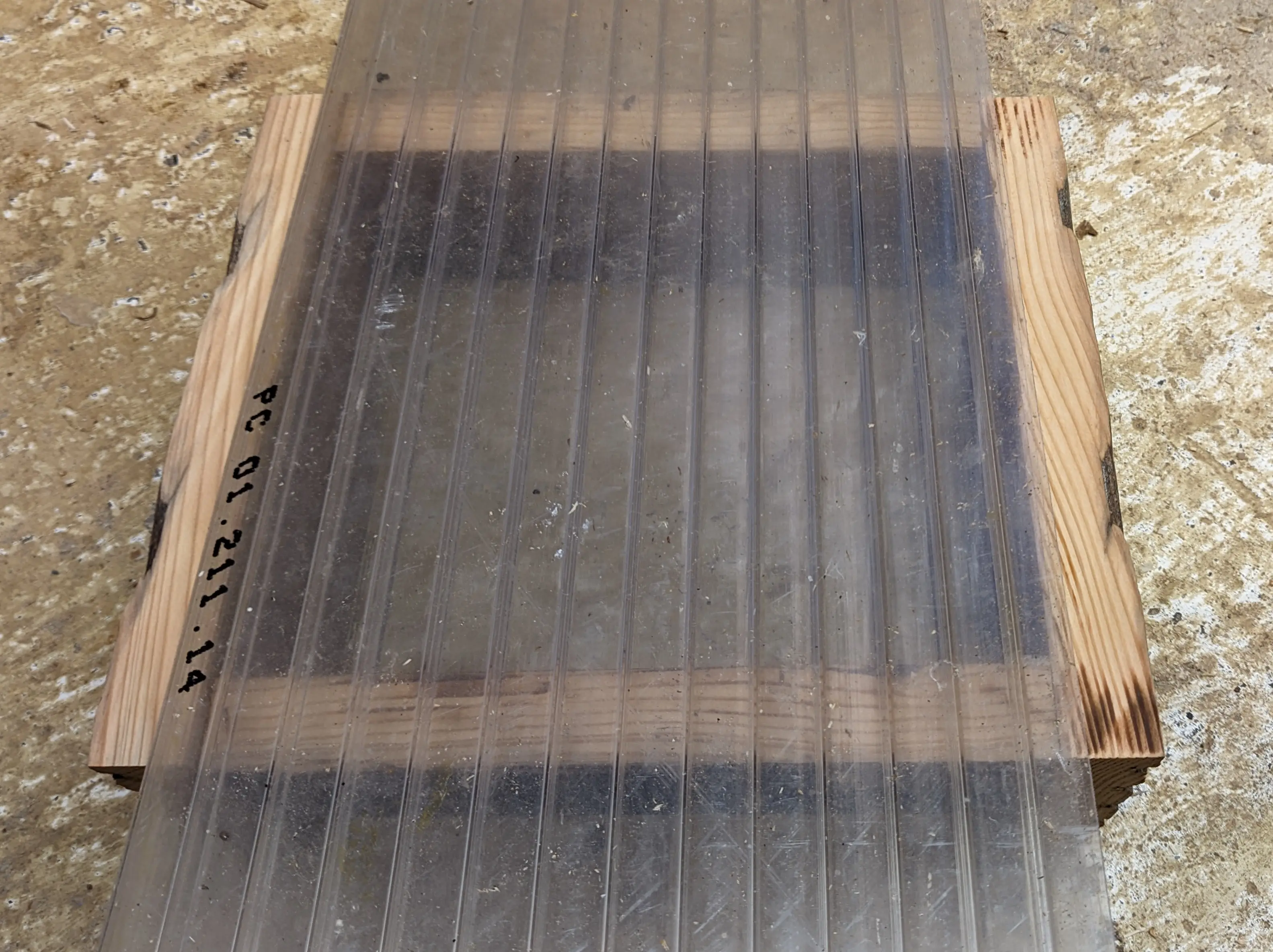 Plastic sheet sitting on top of the assembled hut, with 1-2 cm of wood showing either side.