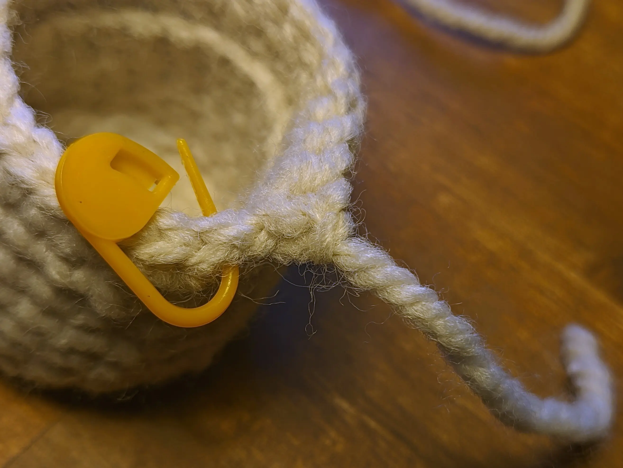 The cylinder walls have been extended, creating a line two rows from the top, where the unused inner loops are visible.
The last stitch of the row has been formed into a slip stitch, with the yarn hanging off and ending after a couple of centimeters.