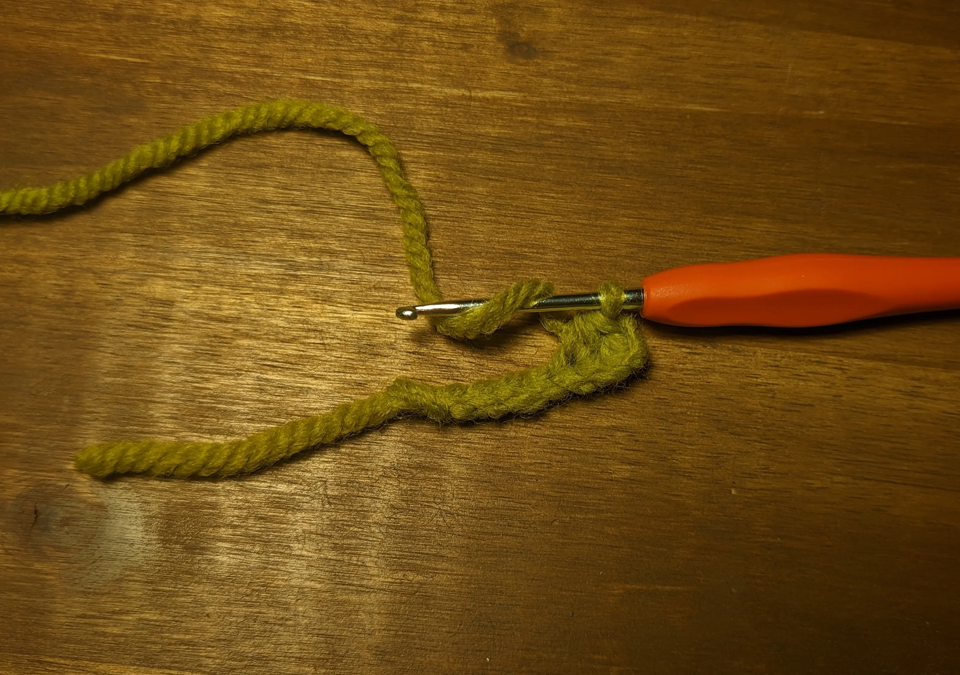 The same chain, but this time, the active yarn has been wrapped around the hook from the back, going back under it from the front.