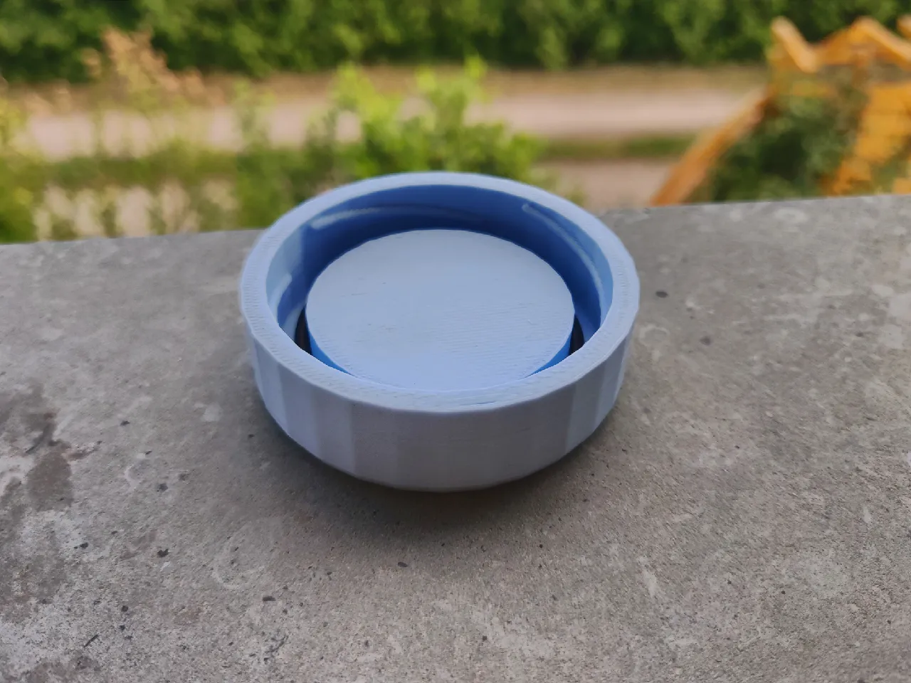 Blue 3D-printed cap from a 45 degree angle, showing the threads spiraling up the inside wall