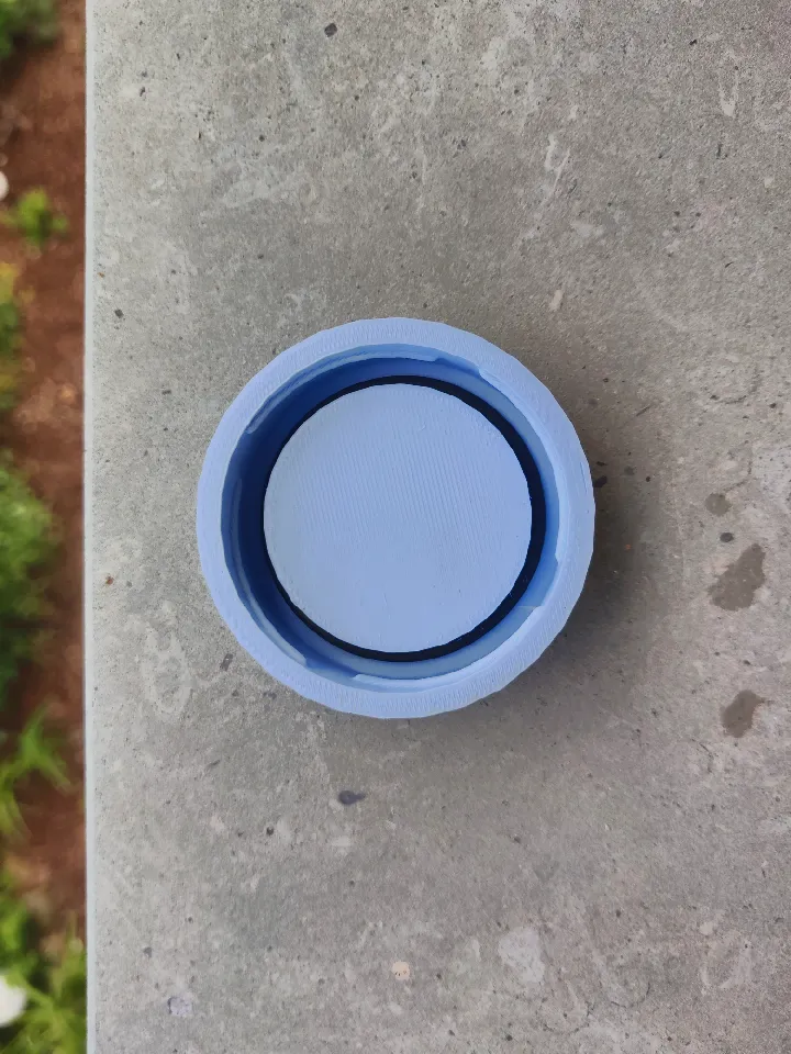 The same blue 3D-printed cap from directly above, showing a black rubber gasket which has been placed around the inner core.