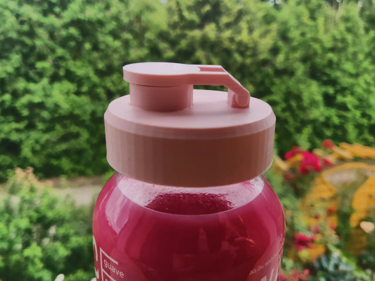 3D printed plastic cap screwed on top of a smoothie bottle. The wide mouth piece extends from the cap as well as a smaller mount, where the lid hinges in. The lid is pressed into the mouthpiece, closing the cap.