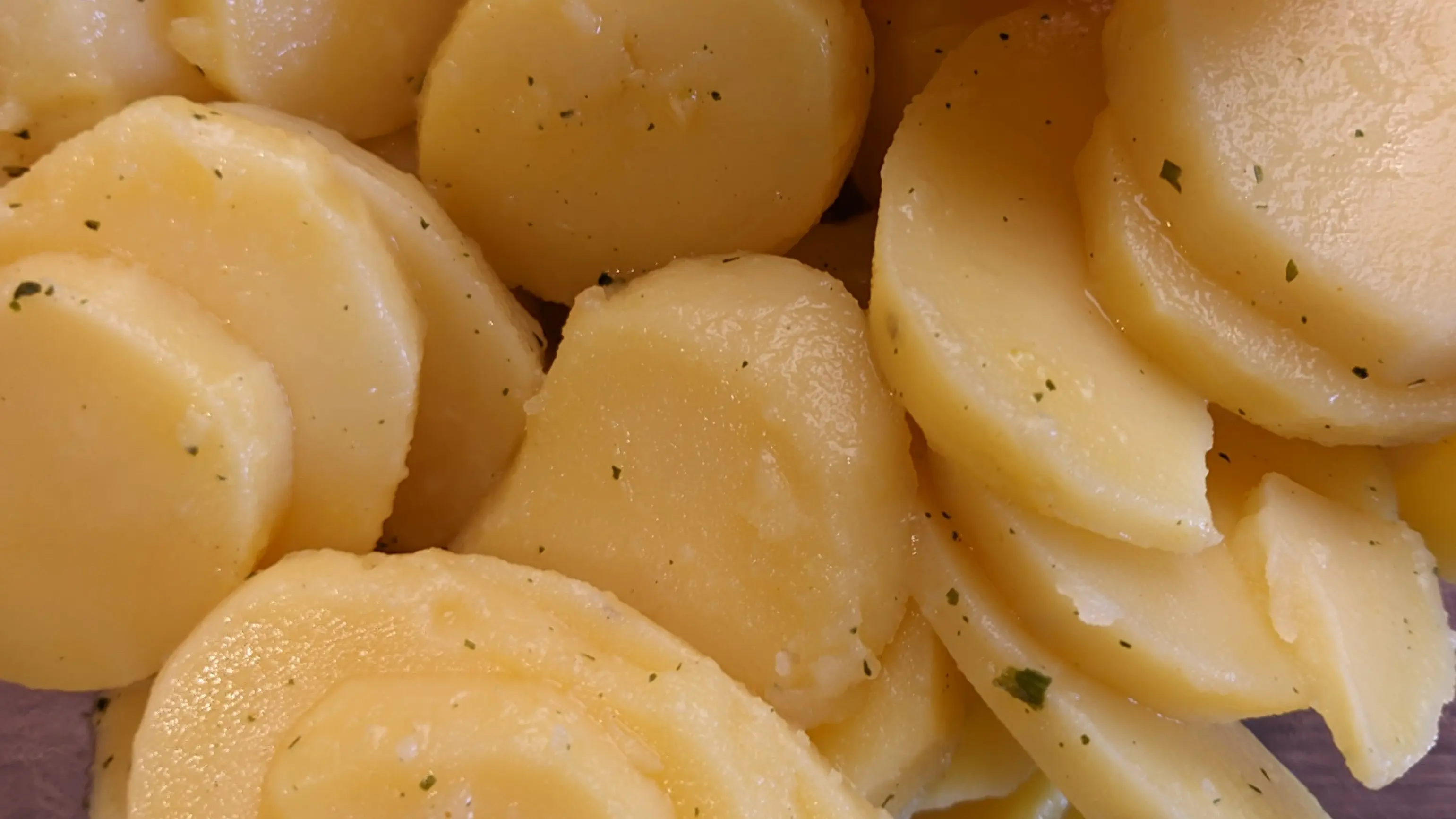 Closeup of potato slices. The potatoes have a sheen to them from the vegetable stock.